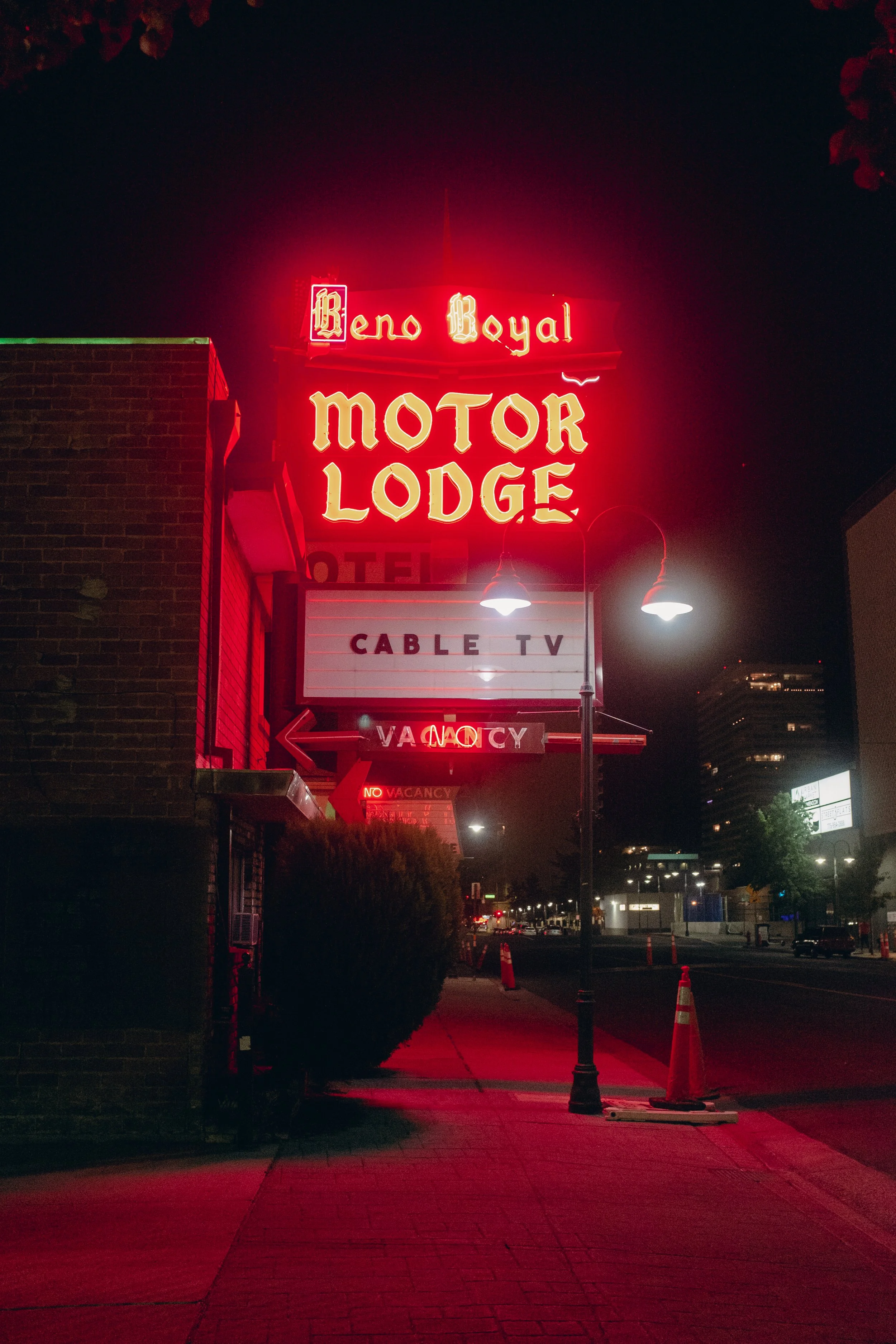 Night view of a neon sign for Beno Royal Motor Lodge on a building, with additional signs indicating a hotel, cable TV, and no vacancy, illuminated in red and yellow lights.