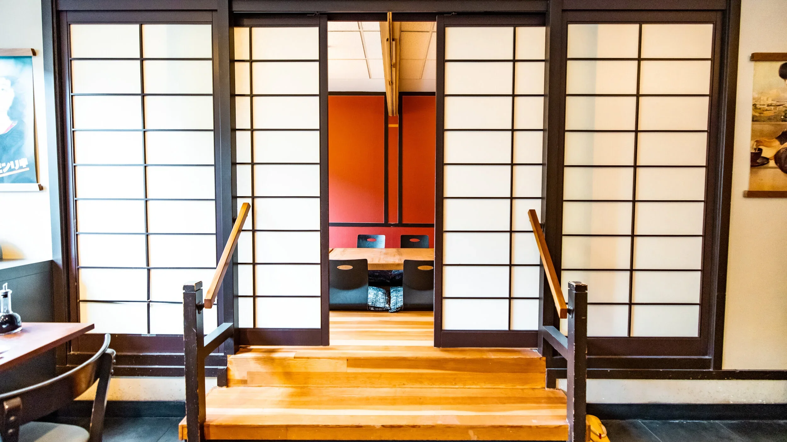 Traditional Japanese-style sliding shoji doors leading into a dining area with low seating and a wooden table.
