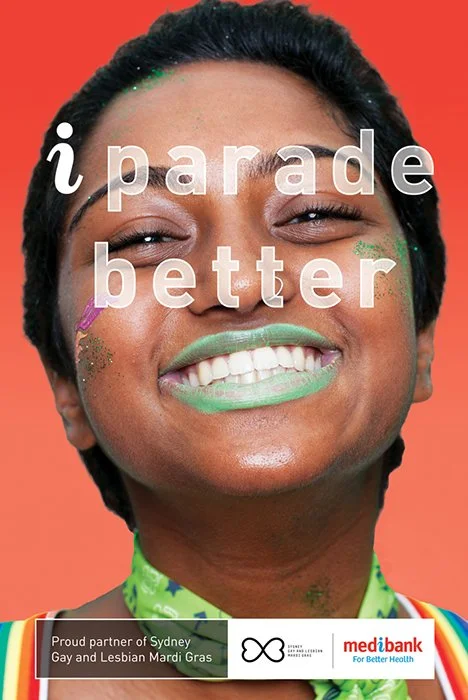 A woman smiling with colorful Mardi Gras face paint, wearing a rainbow-colored shirt, against an orange background. Text on the image says 'parade better.'