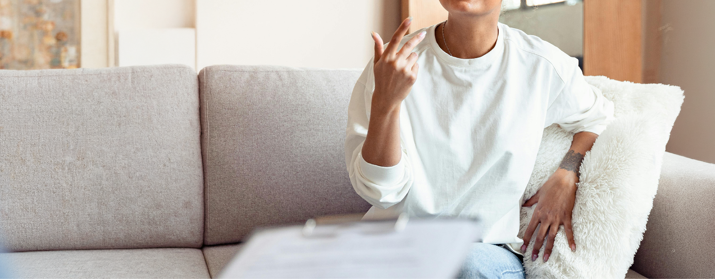 Person speaking and gesturing during a therapy session, seated on a couch in a calm, supportive setting.
