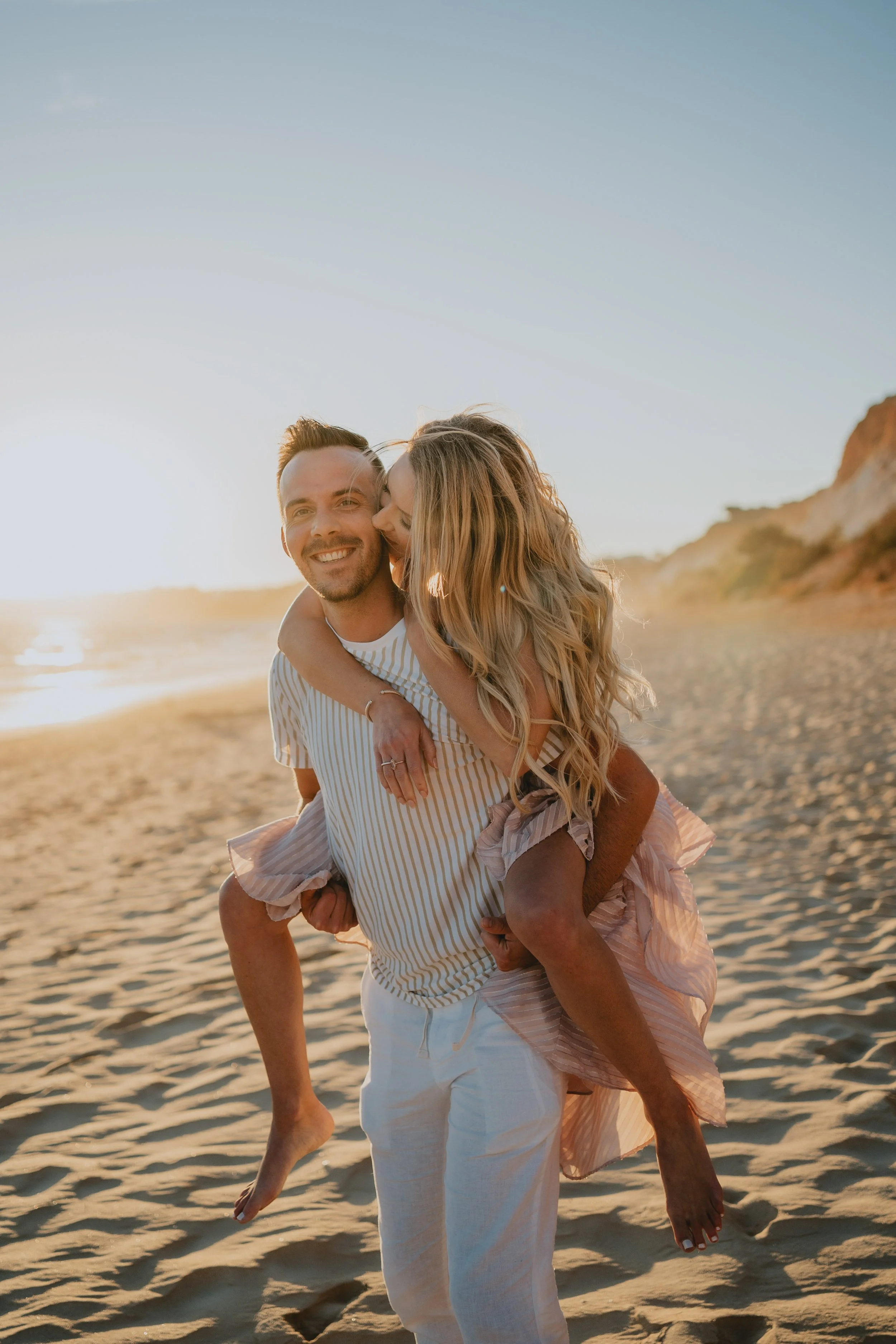 Romantic engagement photography in Algarve, couple standing together by the ocean at sunset.