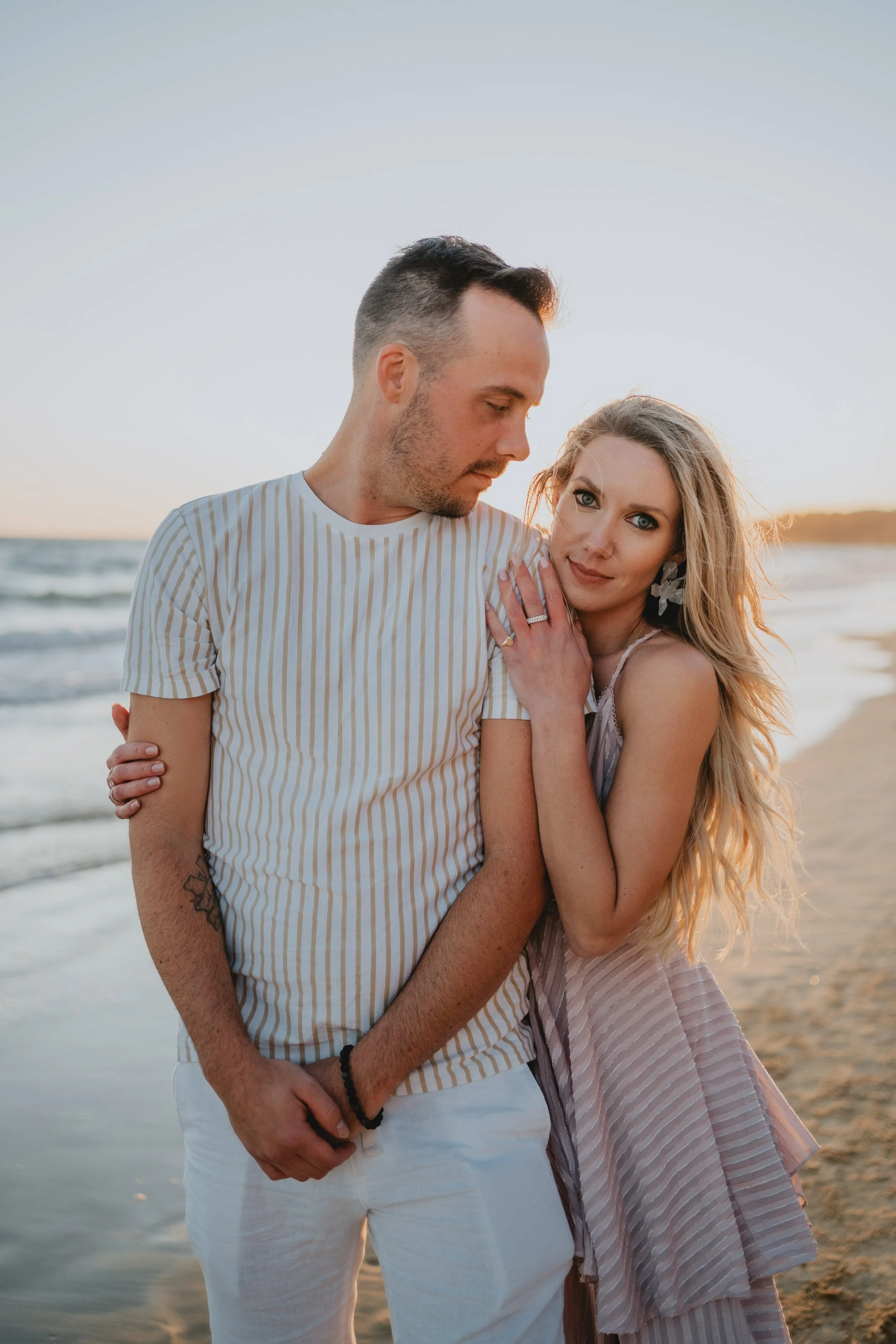 Romantic engagement photography in Algarve, couple standing together by the ocean at sunset.