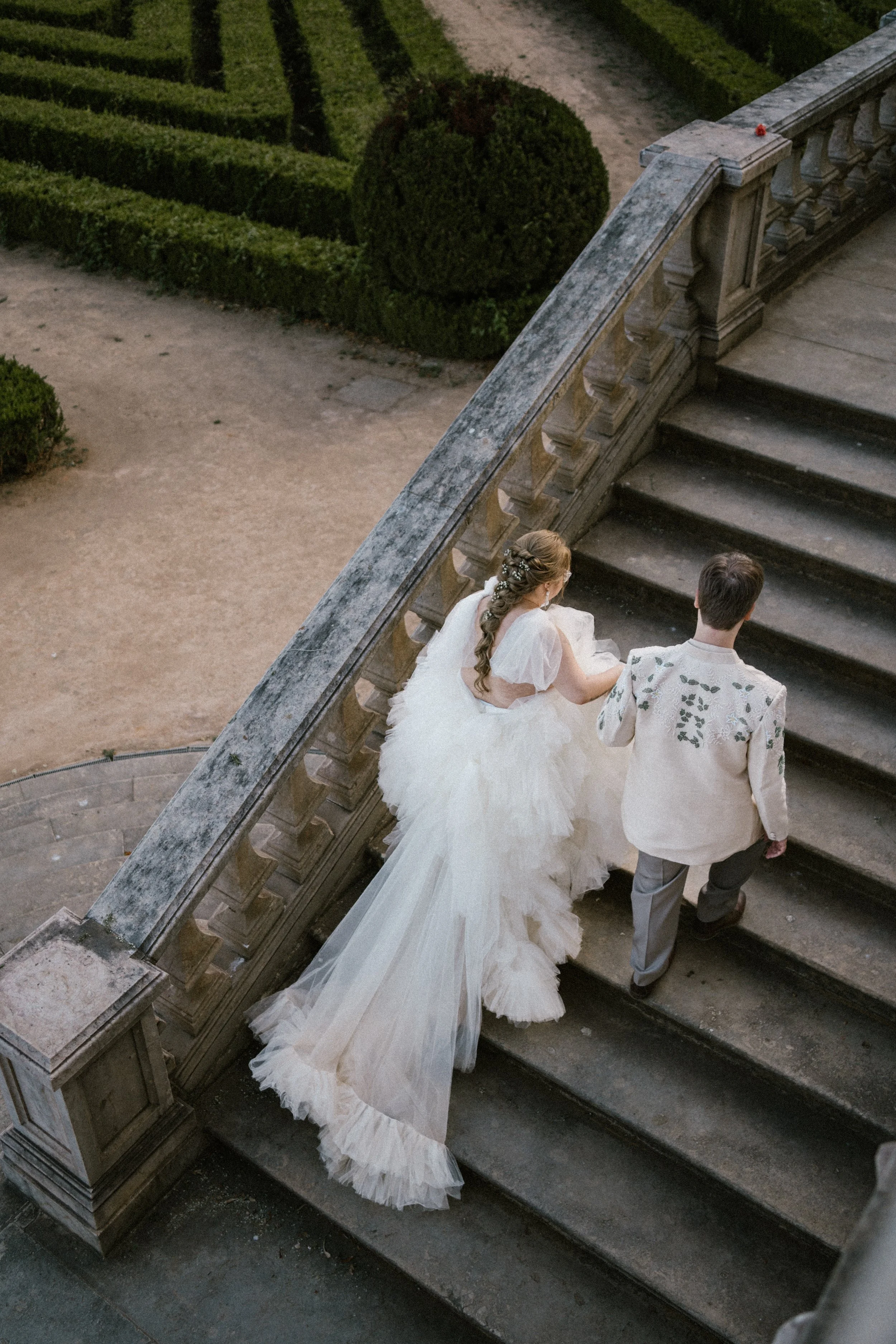 Romantic wedding portrait of bride walking down stone stairs with flowing dress