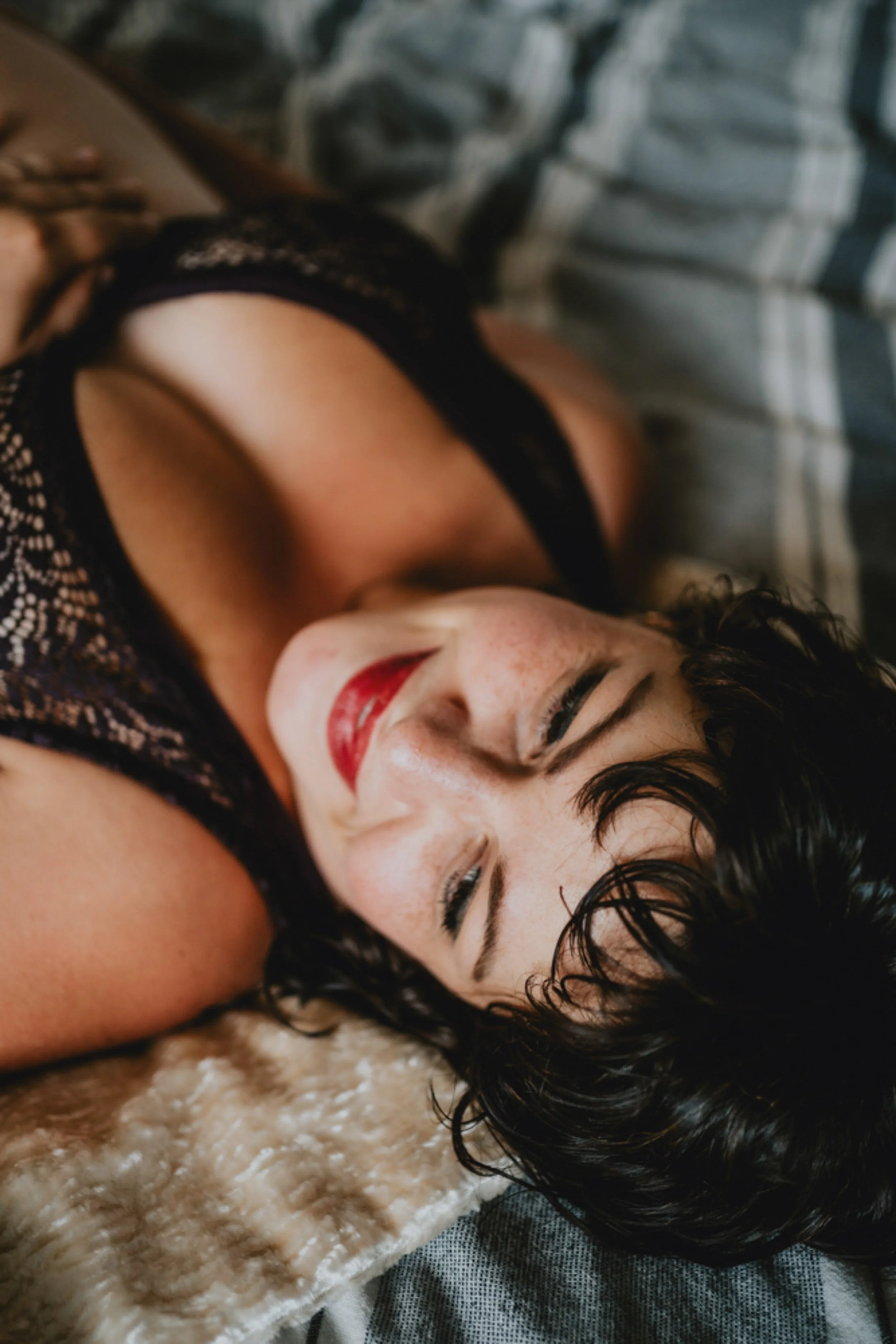 Intimate maternity boudoir photography capturing pregnant woman on bed in soft natural light.