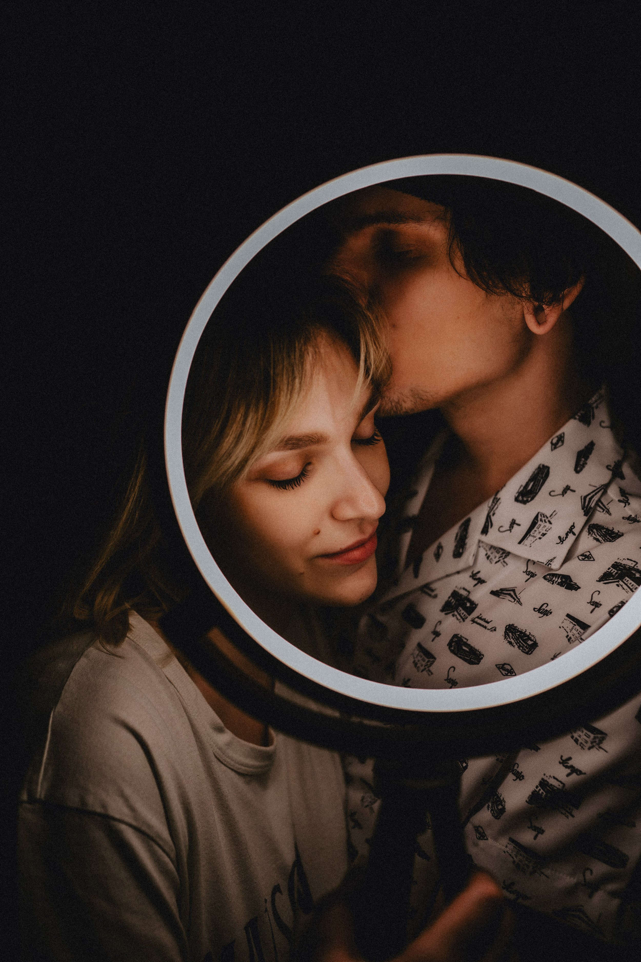 Moody engagement photography portrait of couple sharing intimate moment in creative lighting setup.
