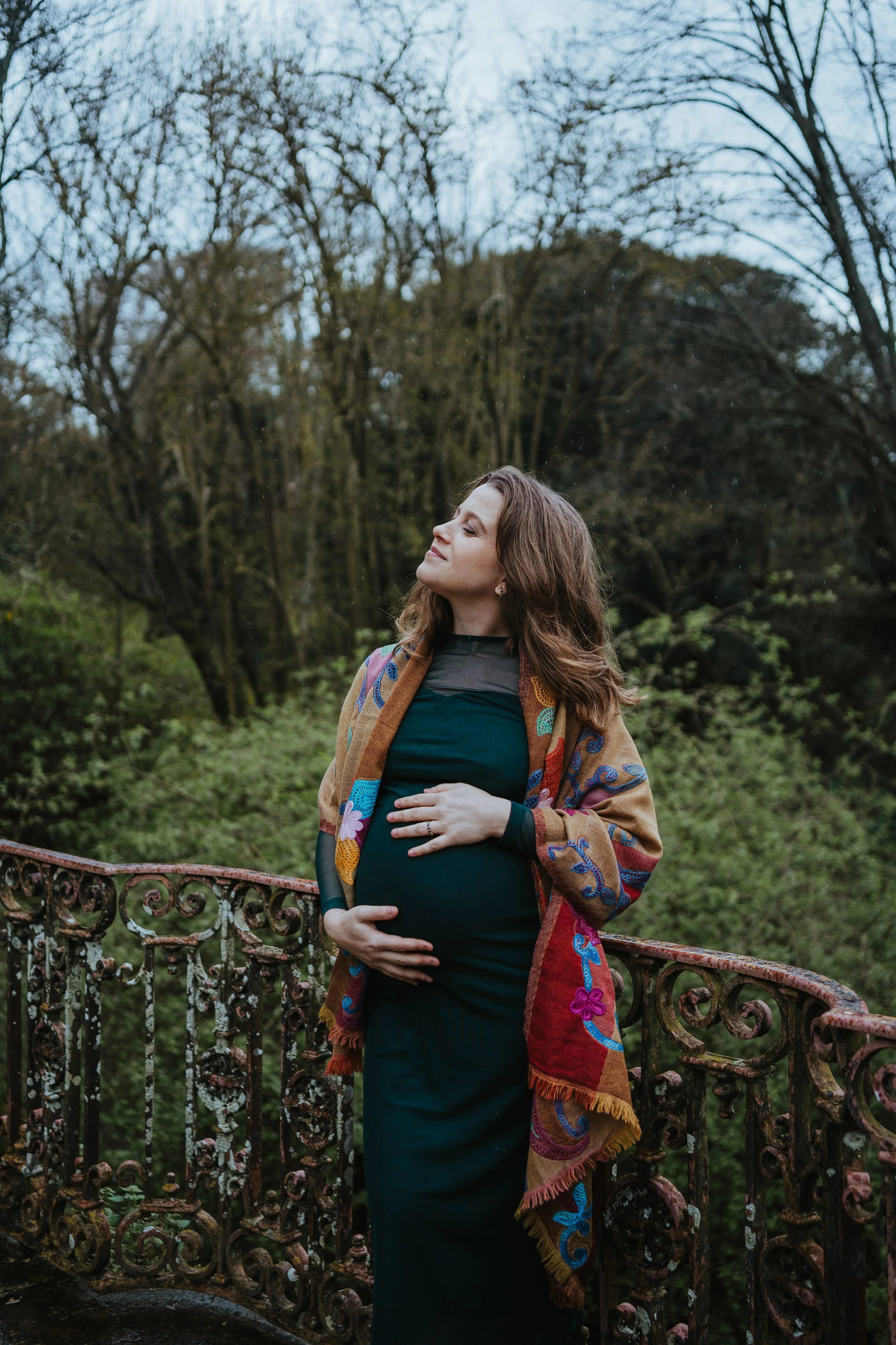 Lifestyle maternity photoshoot in Portugal showing pregnant woman in green dress surrounded by nature.
