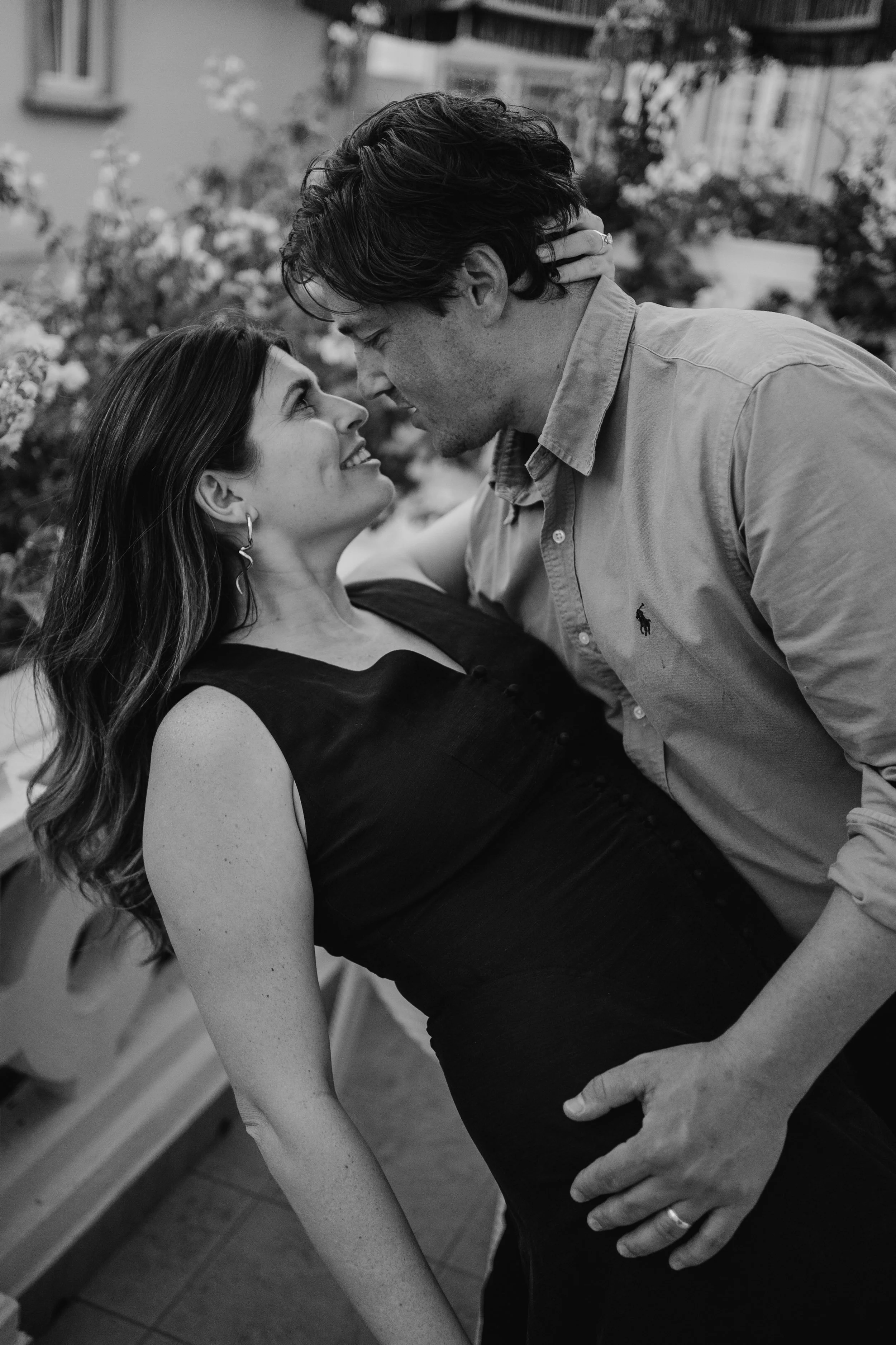 Black and white engagement photography portrait of couple sharing intimate moment during candid session.