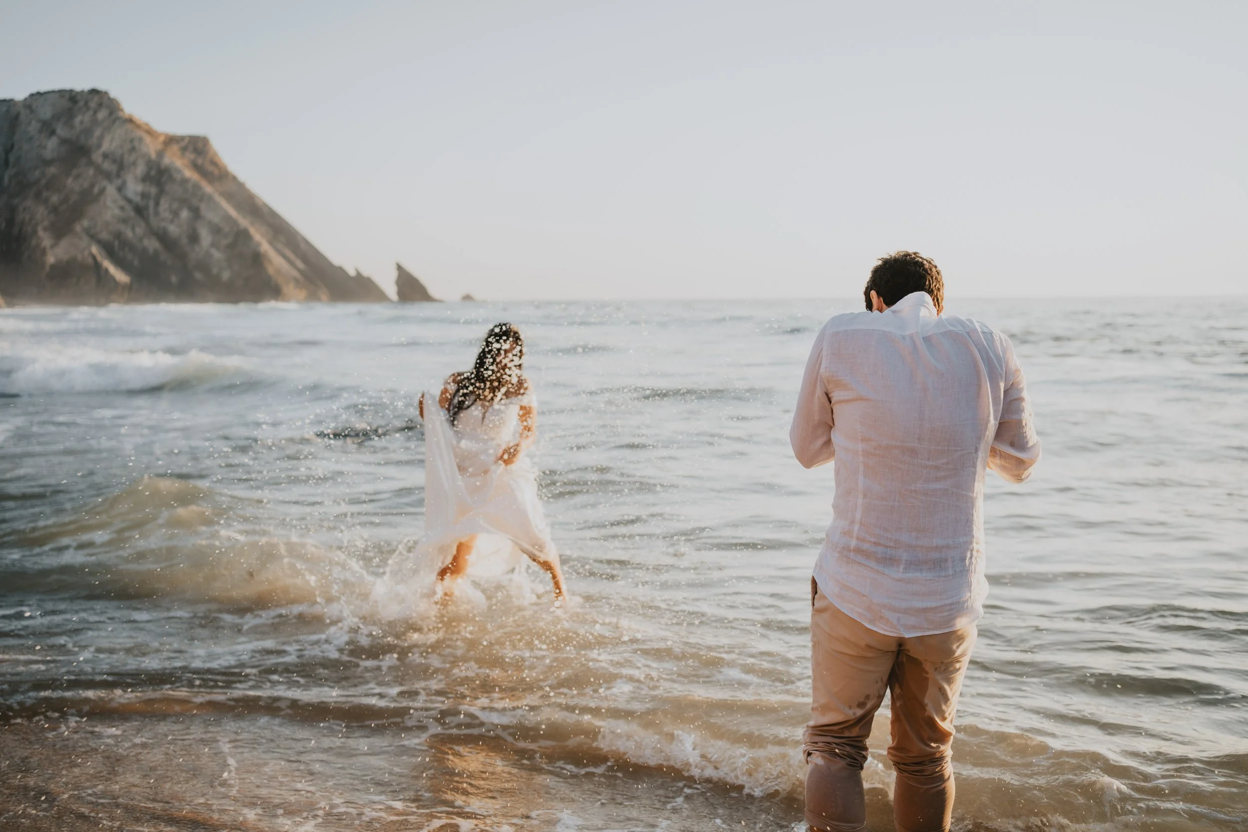 Adventure elopement couple playing barefoot on Adraga Beach 
