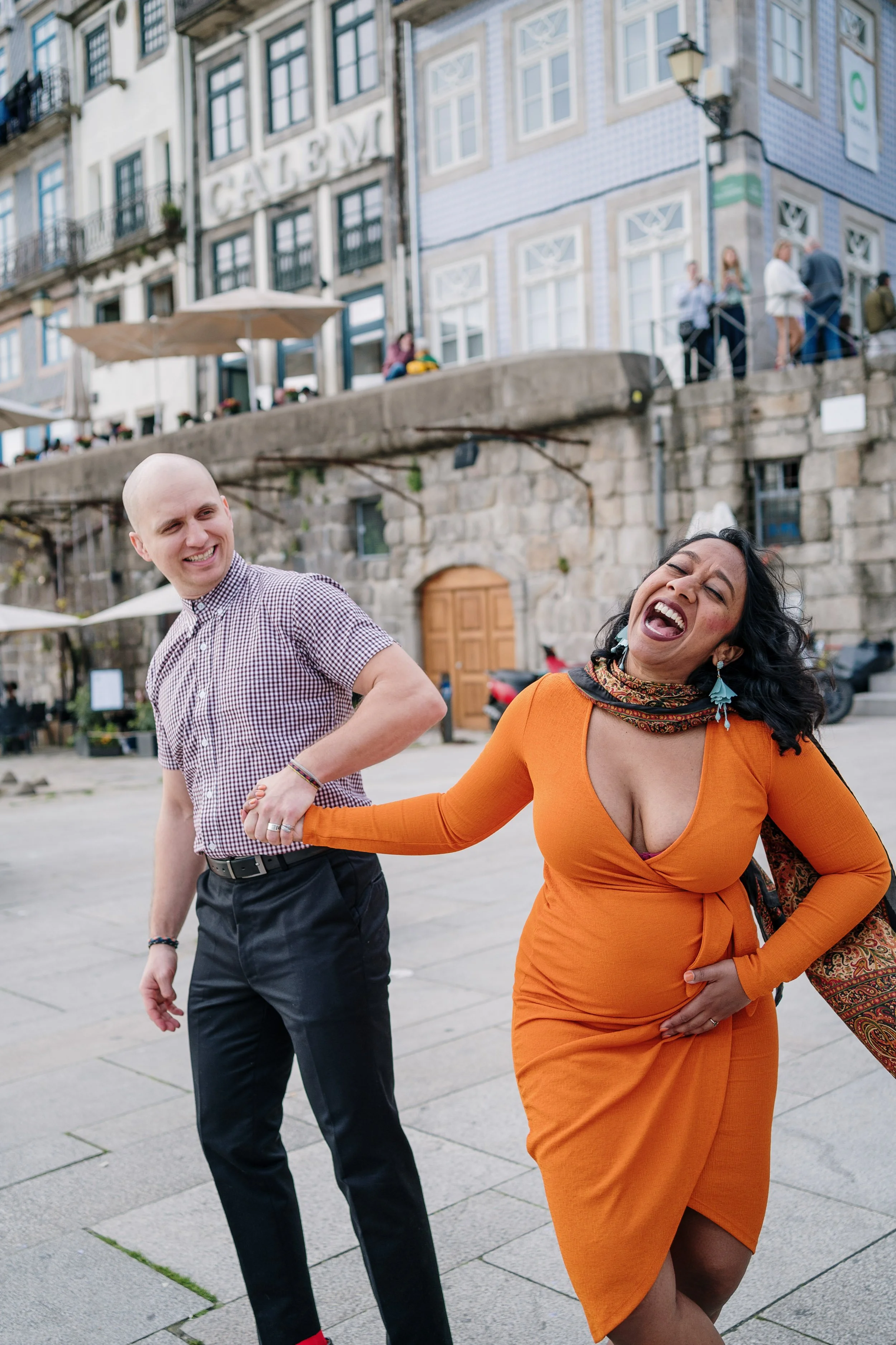 Engagement photography in Lisbon, couple laughing together during city street session.