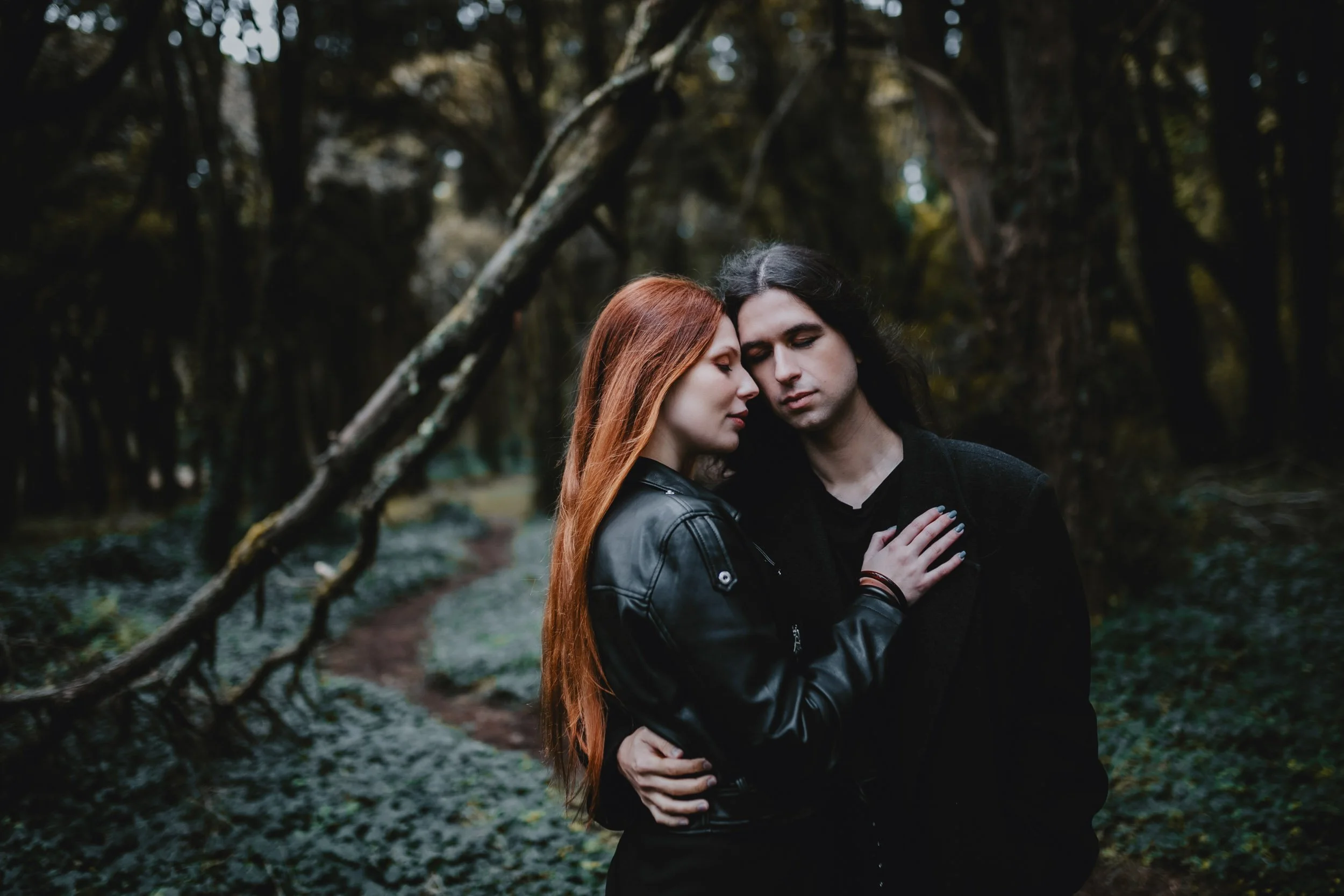 Engagement photography in Sintra forest, couple embracing among lush trees.