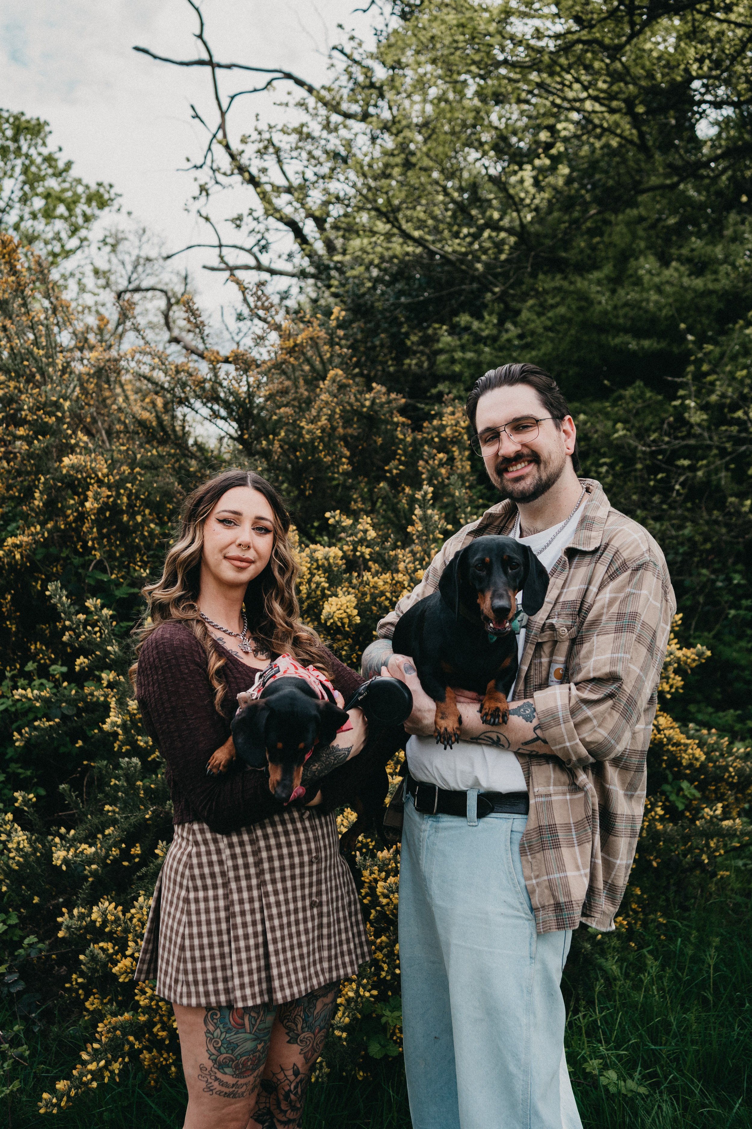 Engagement photography in London, couple posing outdoors with their dogs during natural countryside session.