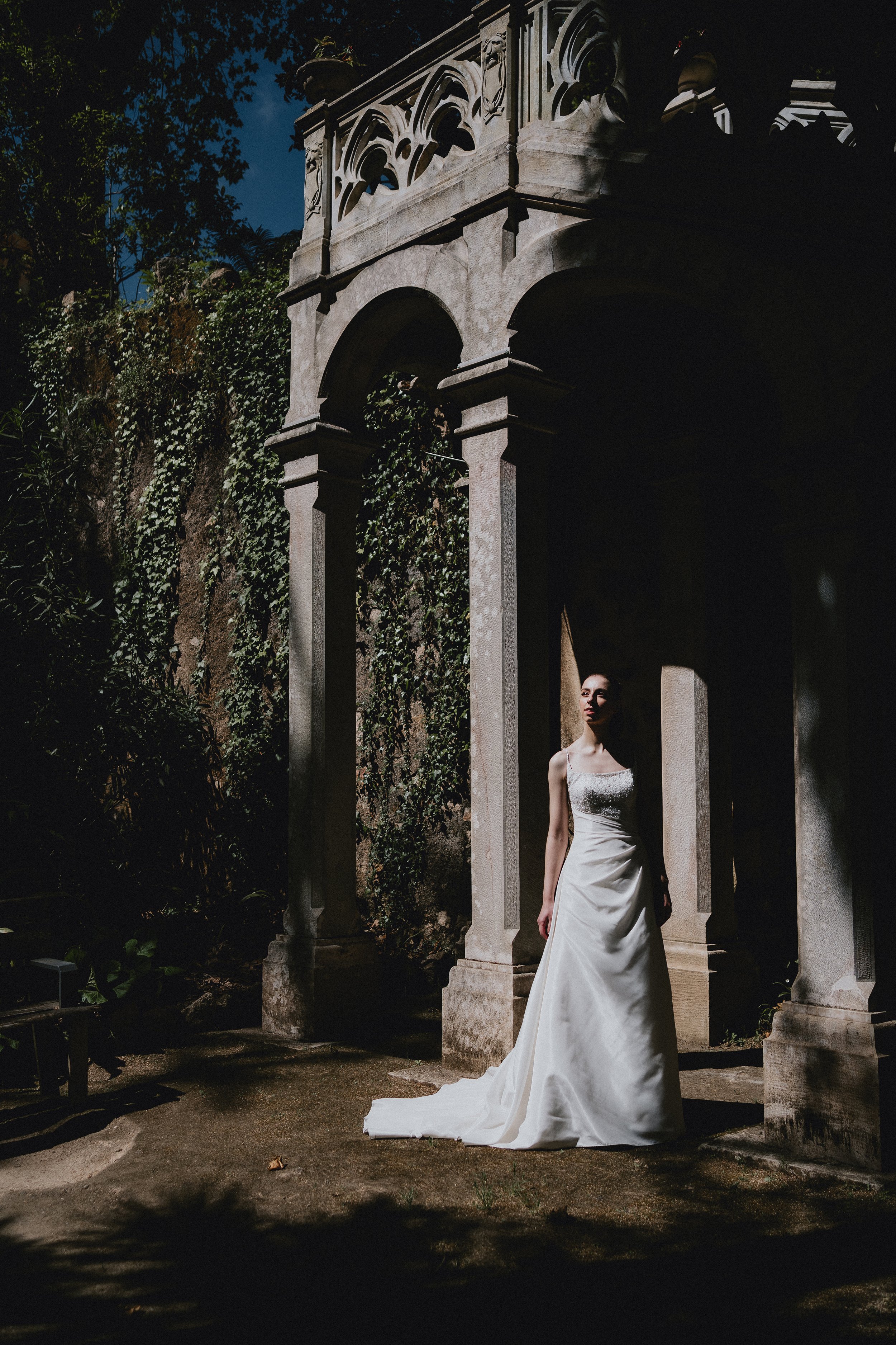 Bride walking alone during romantic elopement in Portugal with historic architecture