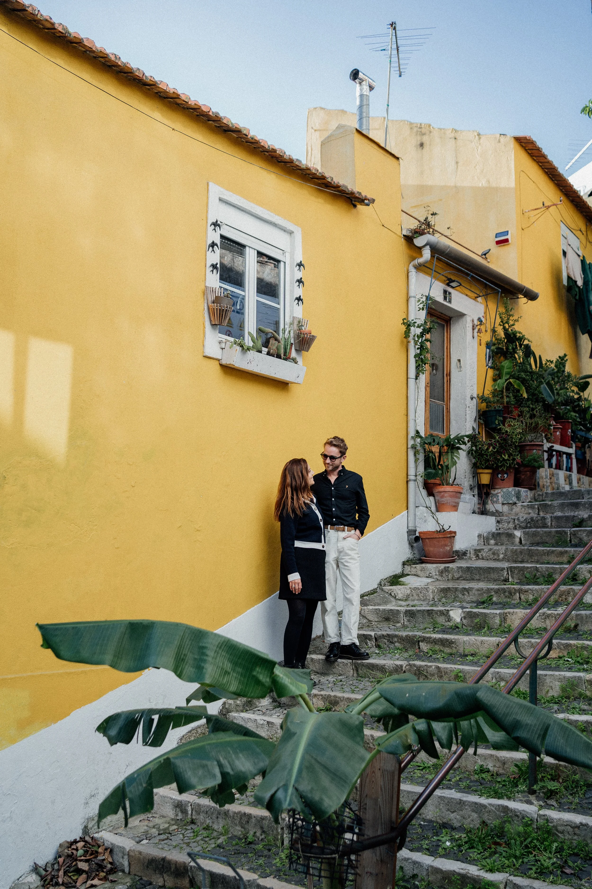 Engagement photography in Lisbon, couple standing against colorful traditional Portuguese building.