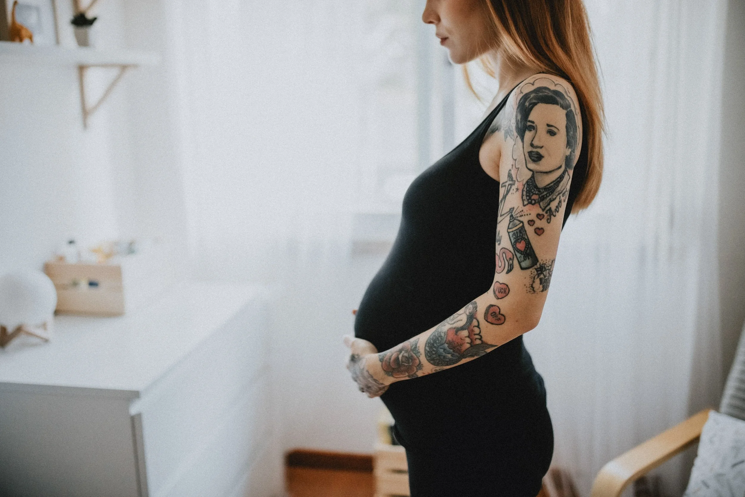 Alternative pregnancy photoshoot done indoors, with a mom with tattoos