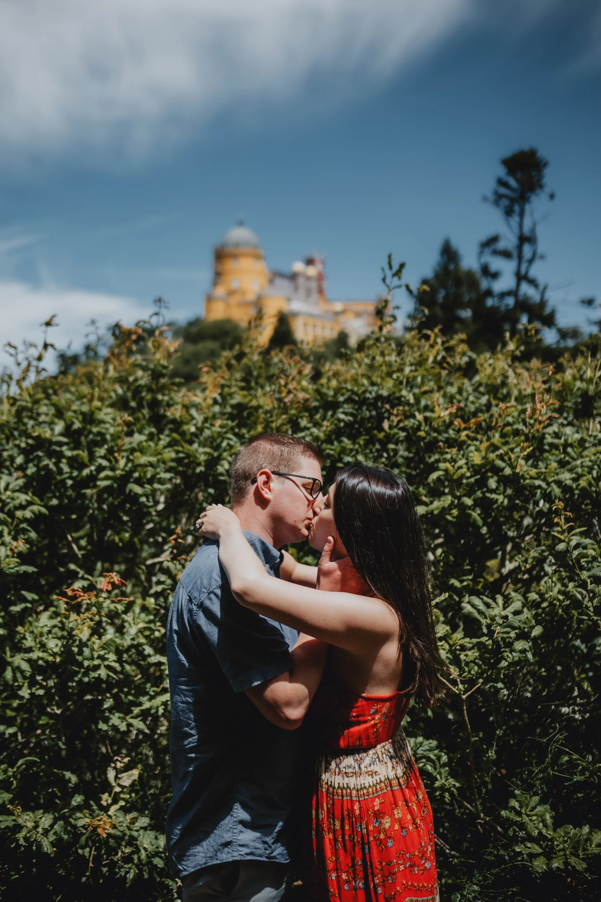 Engagement photography in Sintra, couple kissing with Pena Palace behind them.