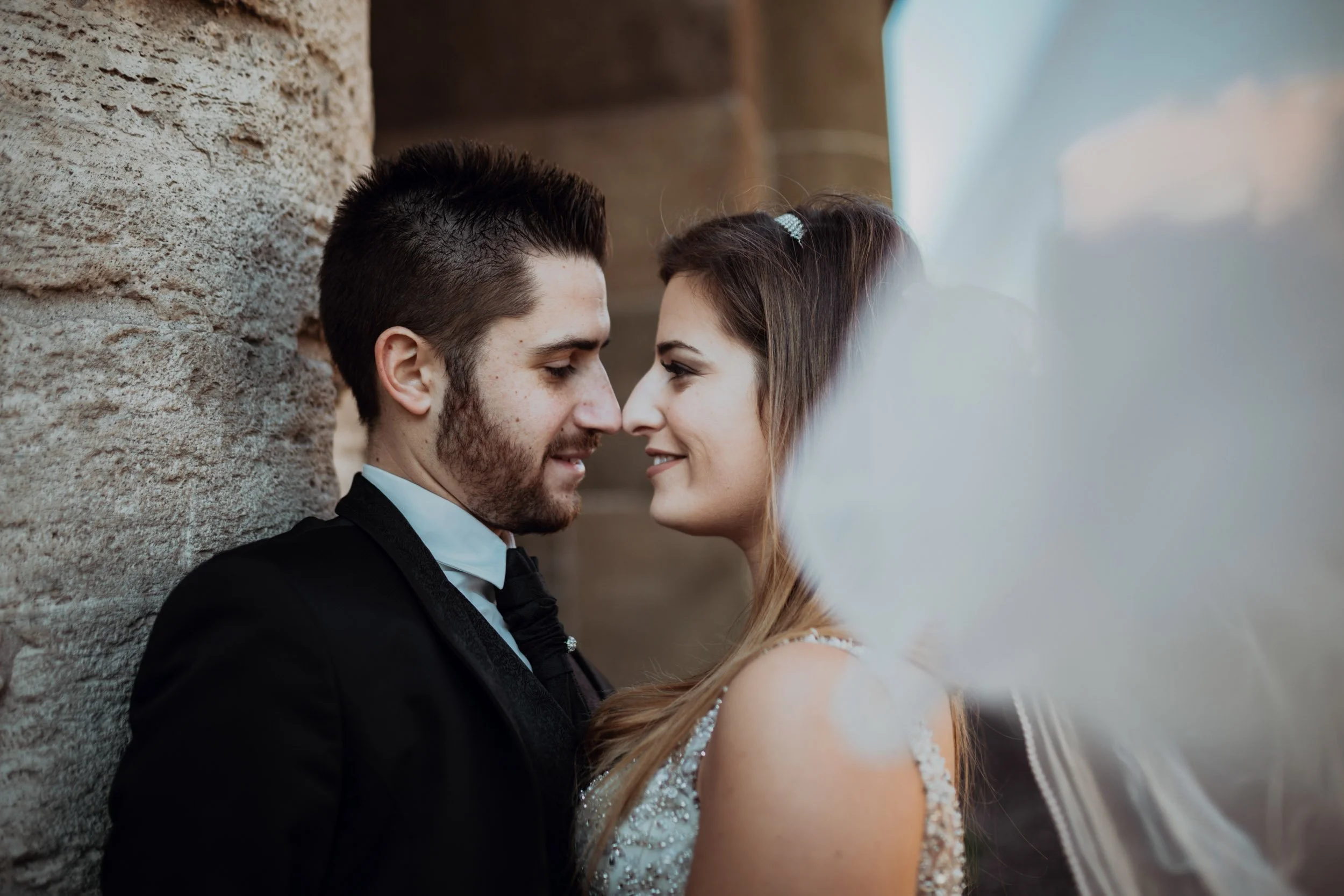 Bride and groom intimate portrait against stone column during Rome destination elopement