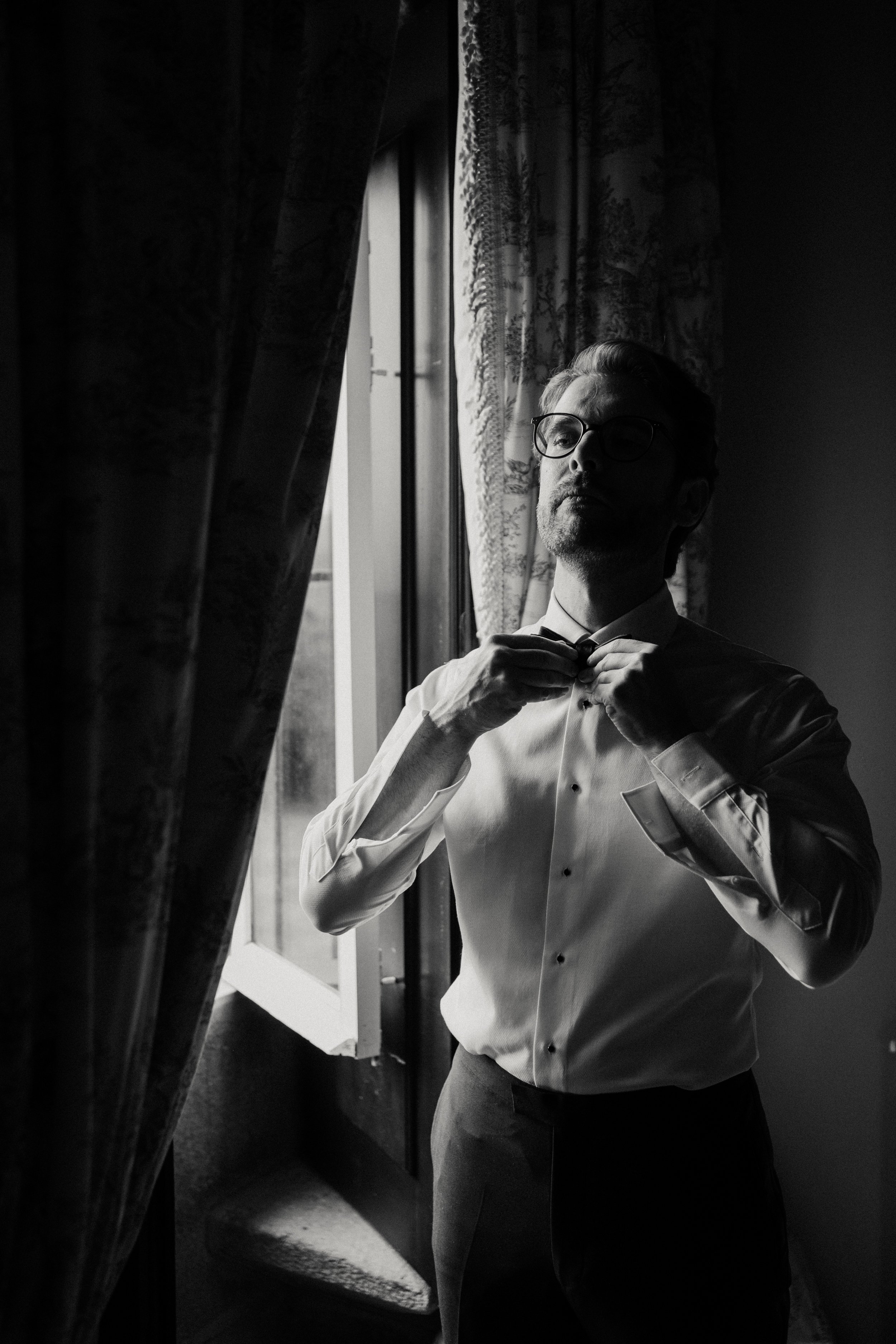 Dramatic black and white portrait of a groom getting ready