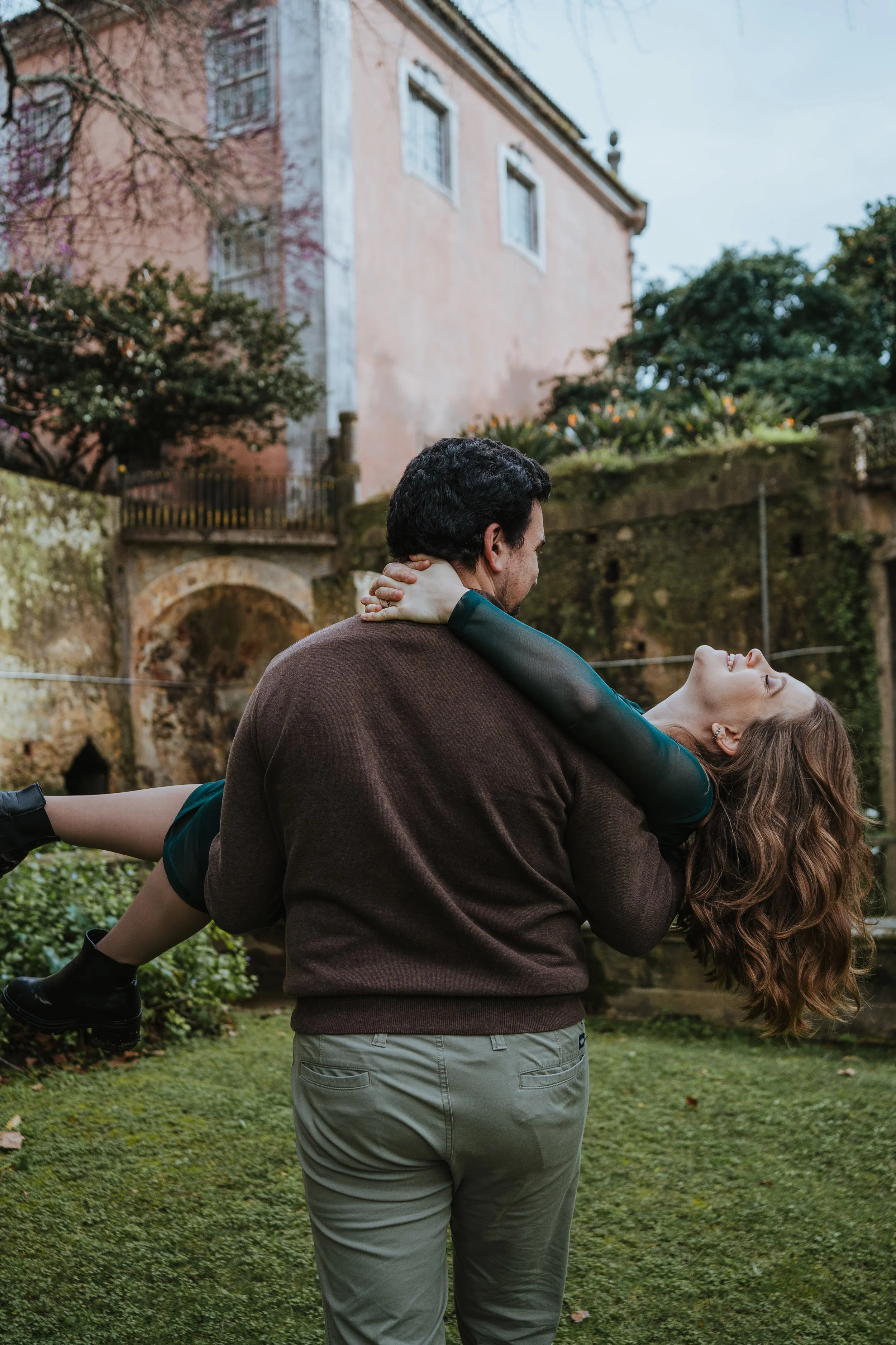 Engagement photography in Portugal, couple embracing and laughing in outdoor nature setting.