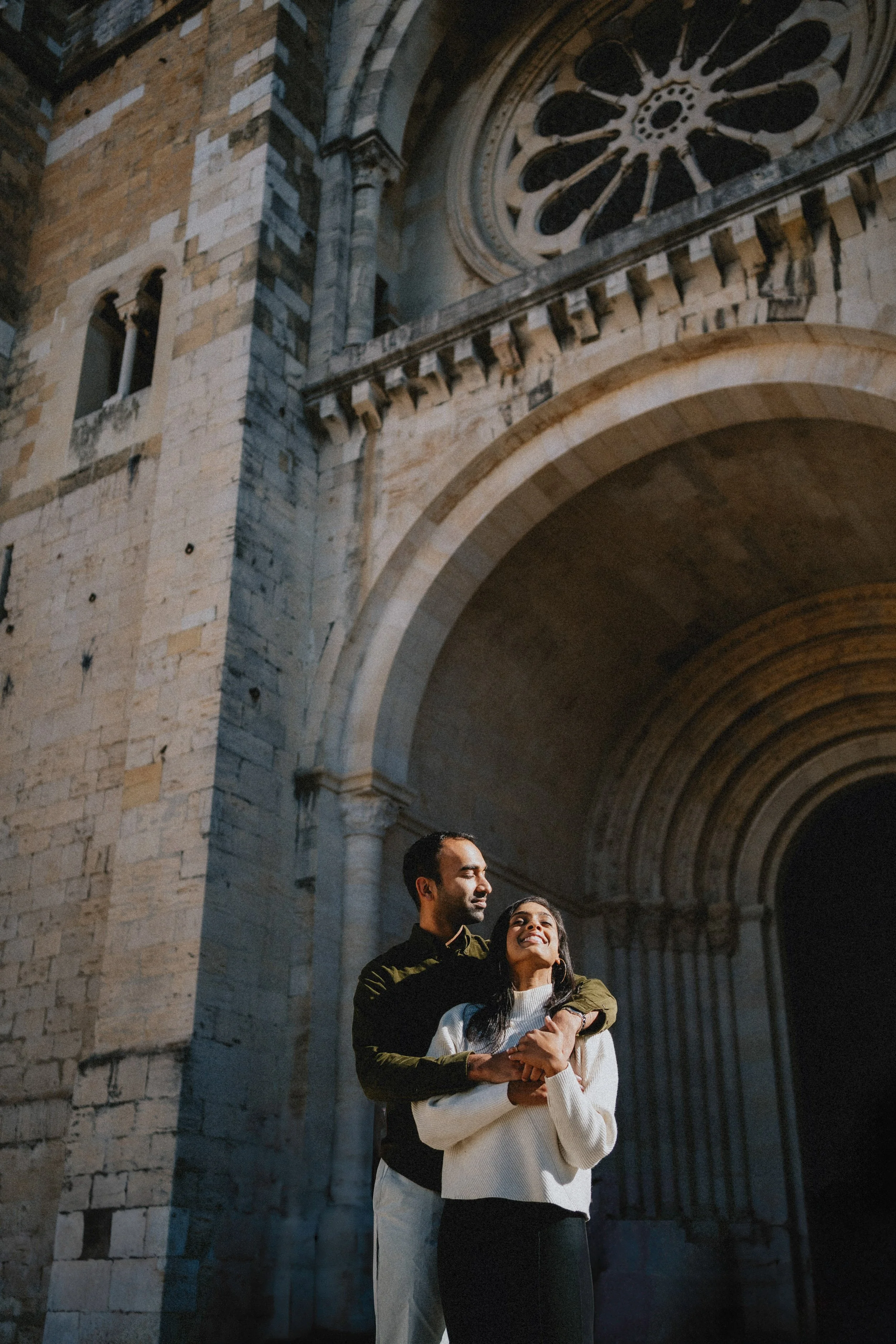 Engagement photography in Lisbon, couple walking together through historic city street.