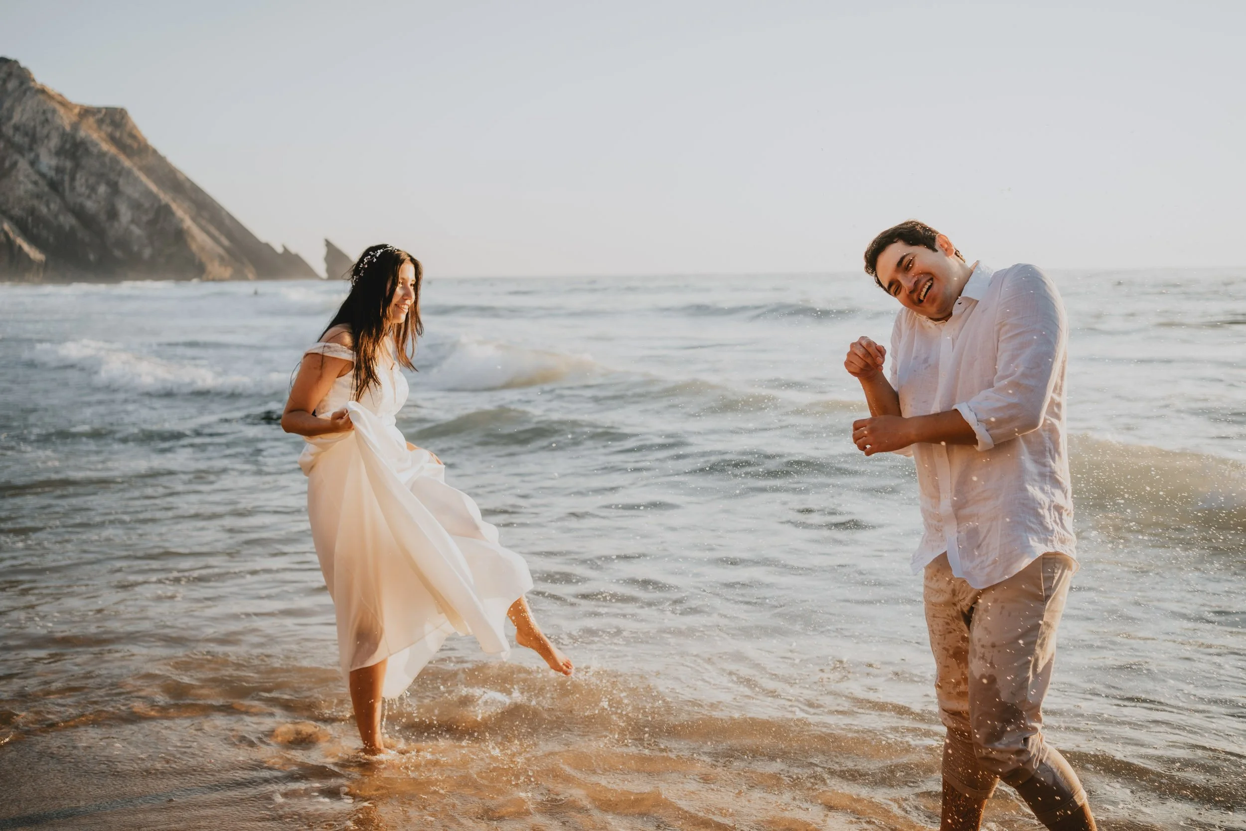 Newly married couple having their fun in the water in Adagra Beach, in Sintra