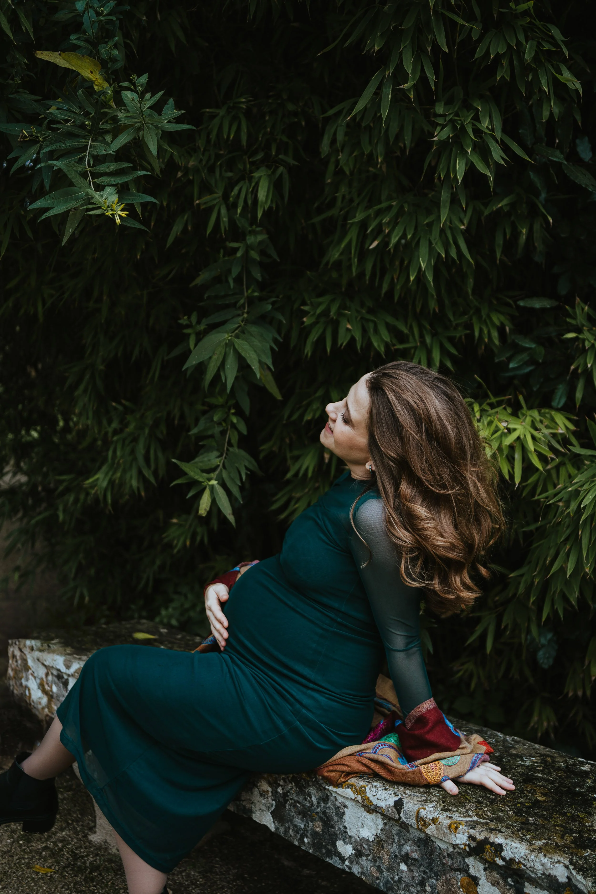Lifestyle maternity photoshoot in Portugal showing pregnant woman in green dress surrounded by nature.