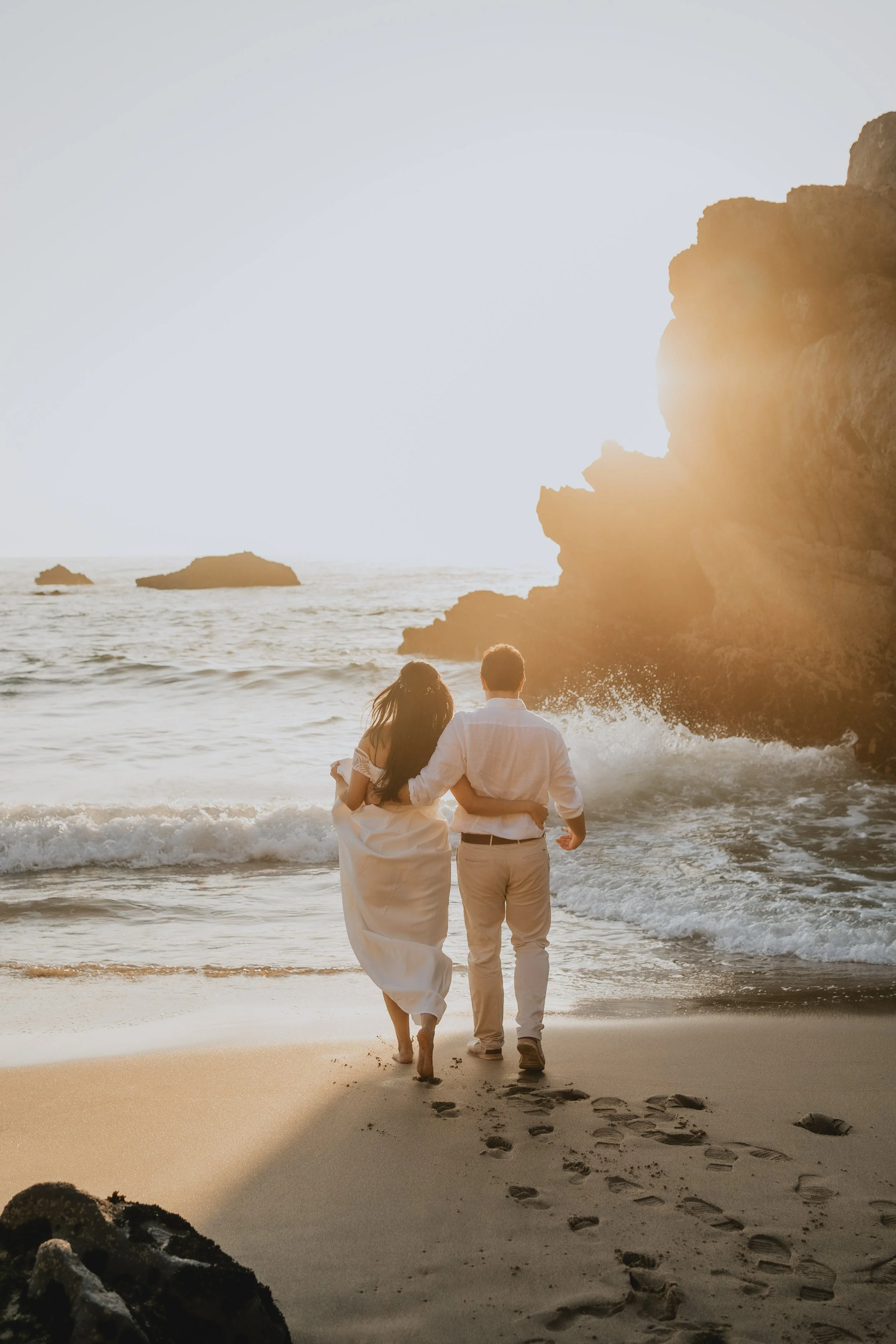 Elopement couple walking hand in hand on Adraga Beach at sunset in Sintra