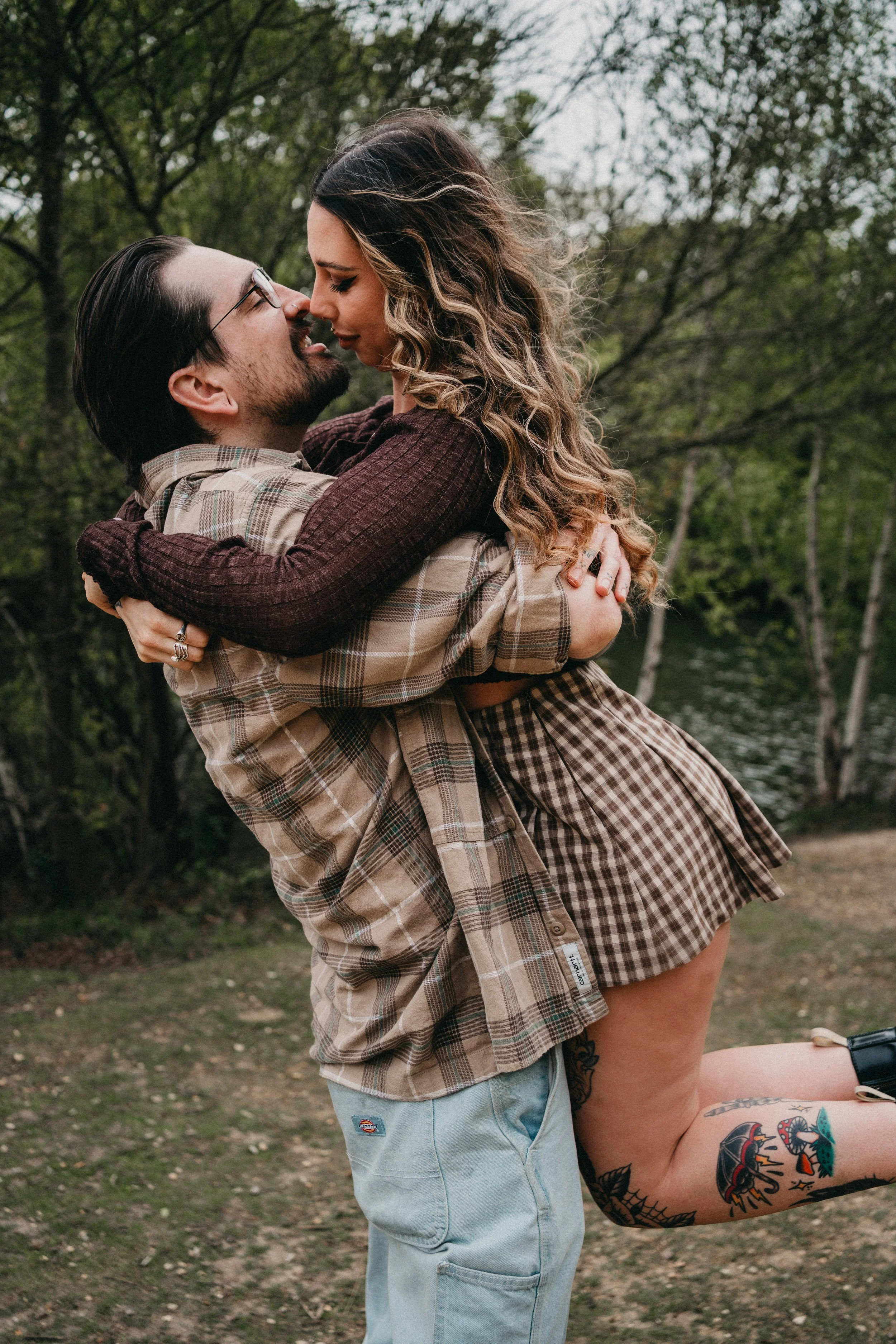 Engagement photography in London, couple embracing during moody woodland session.