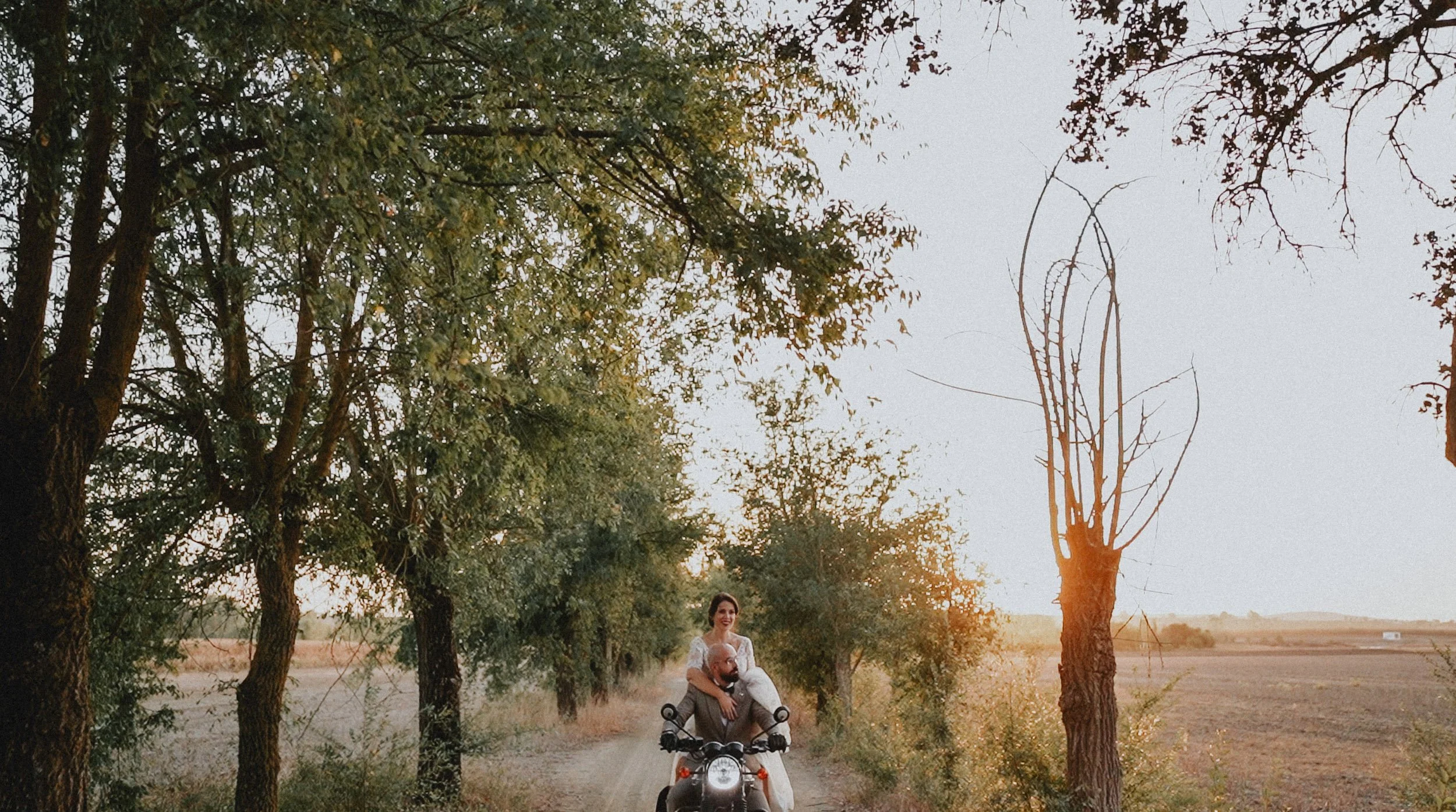 Photograph of a sunset with bride and groom riding a motorcycle