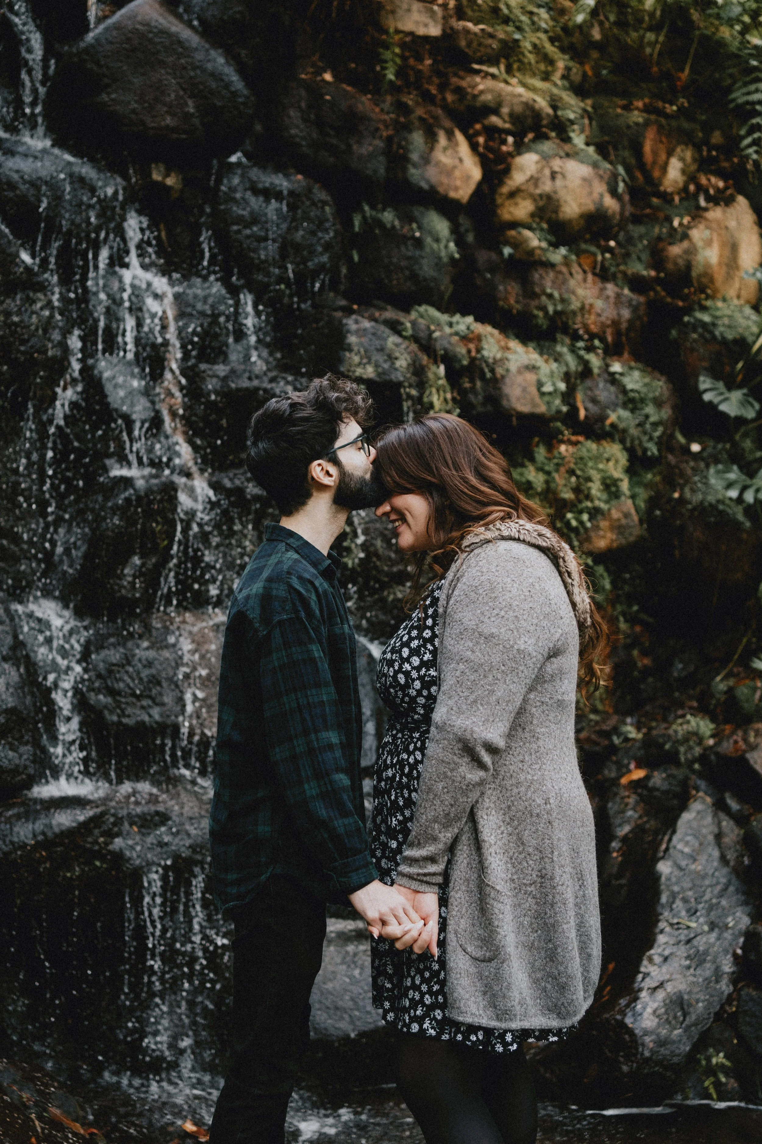 Engagement photography in Sintra, couple kissing near waterfall during moody forest session.