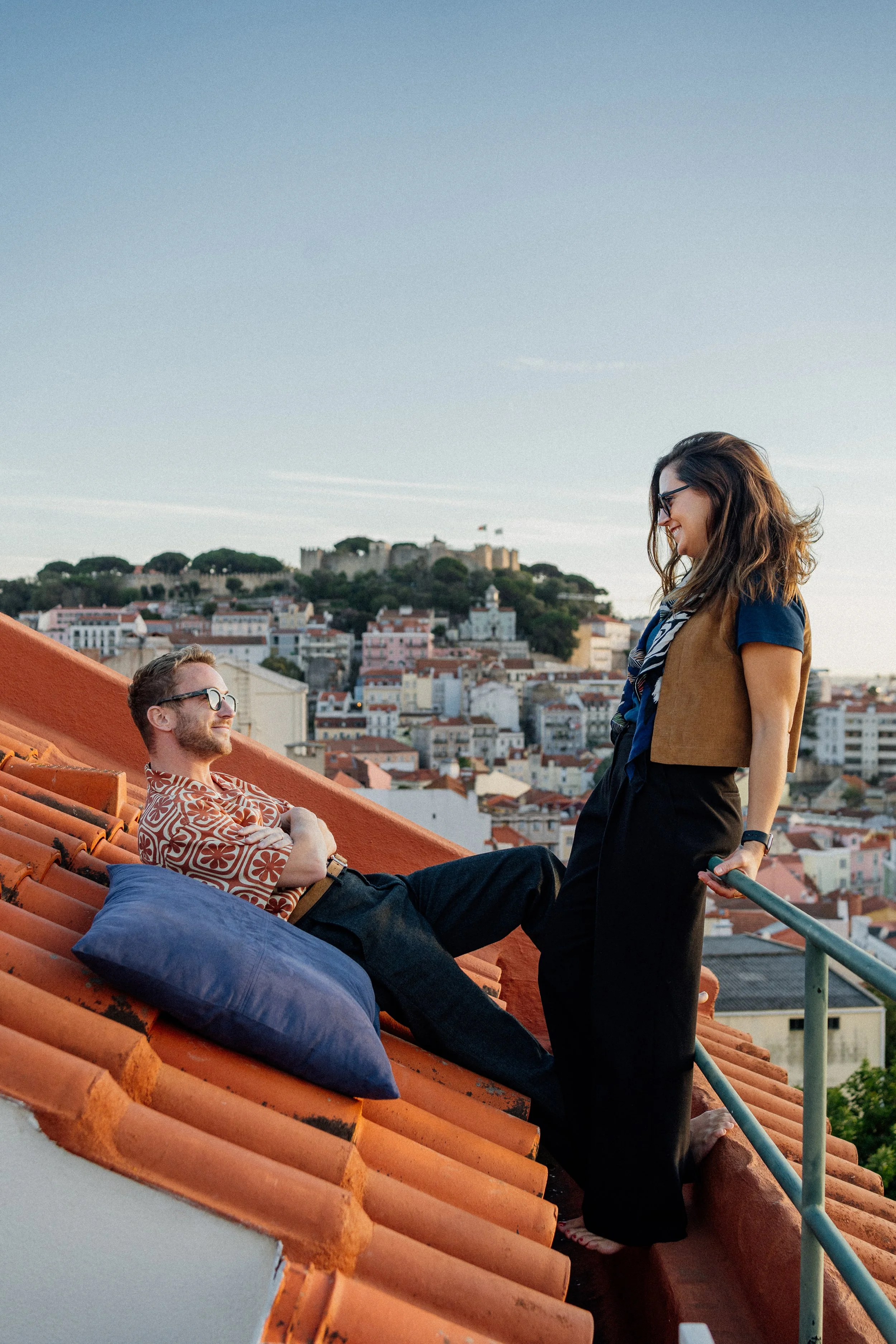 Engagement photography in Lisbon, couple embracing with scenic city view in the background.