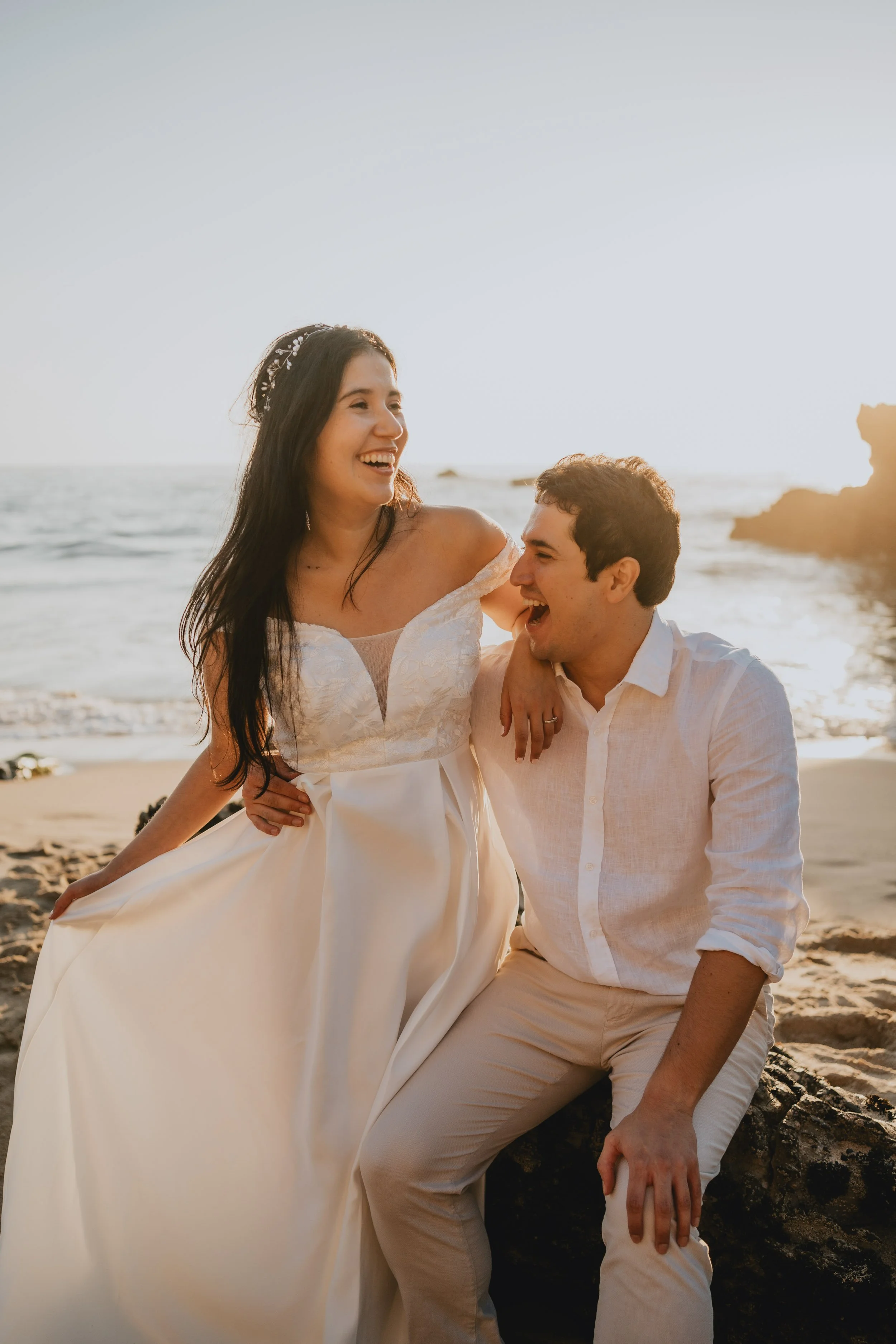 Joyful bride and groom laughing together during sunset elopement at Adraga Beach Sintra