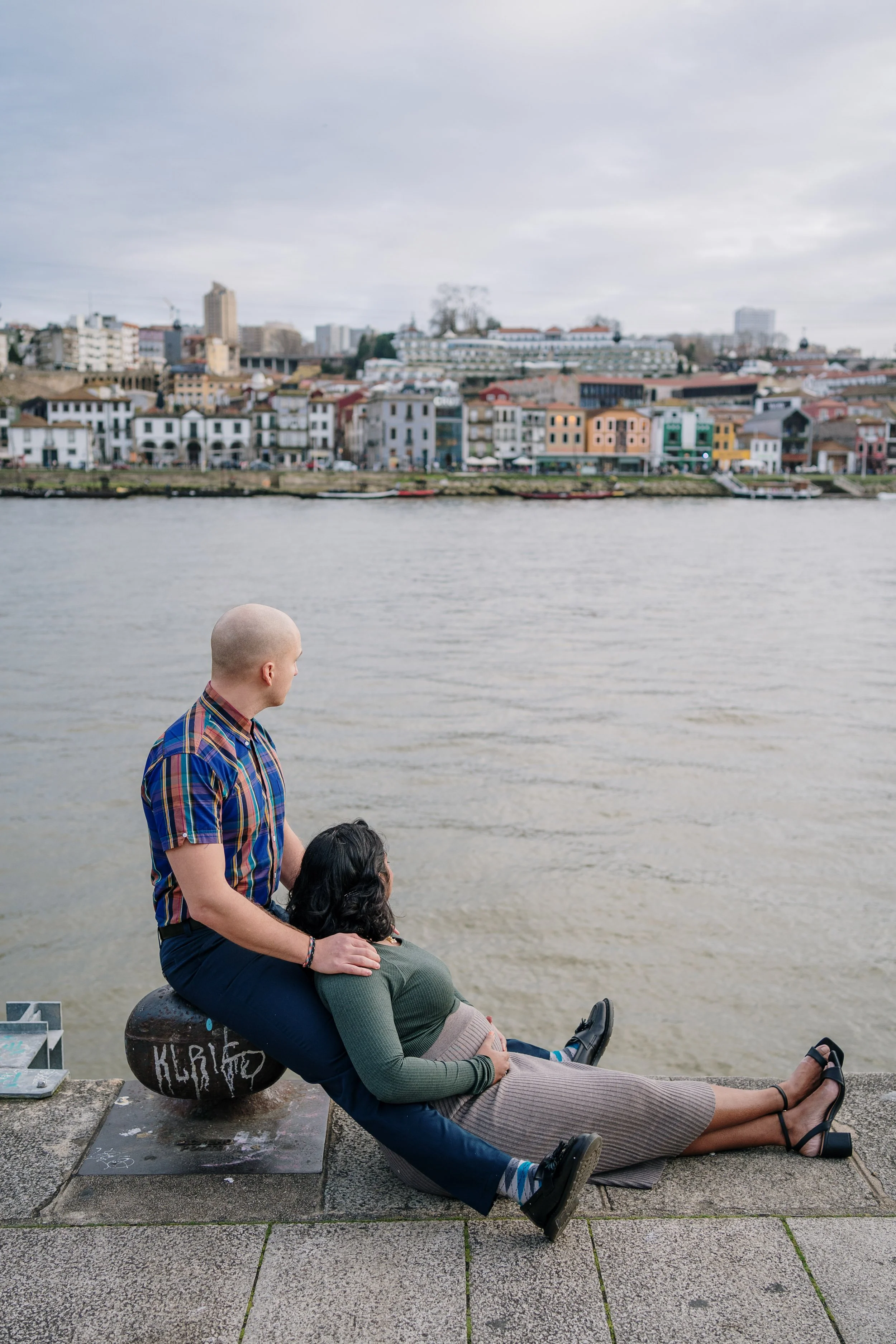 Engagement photography in Porto, couple sitting together along the waterfront.