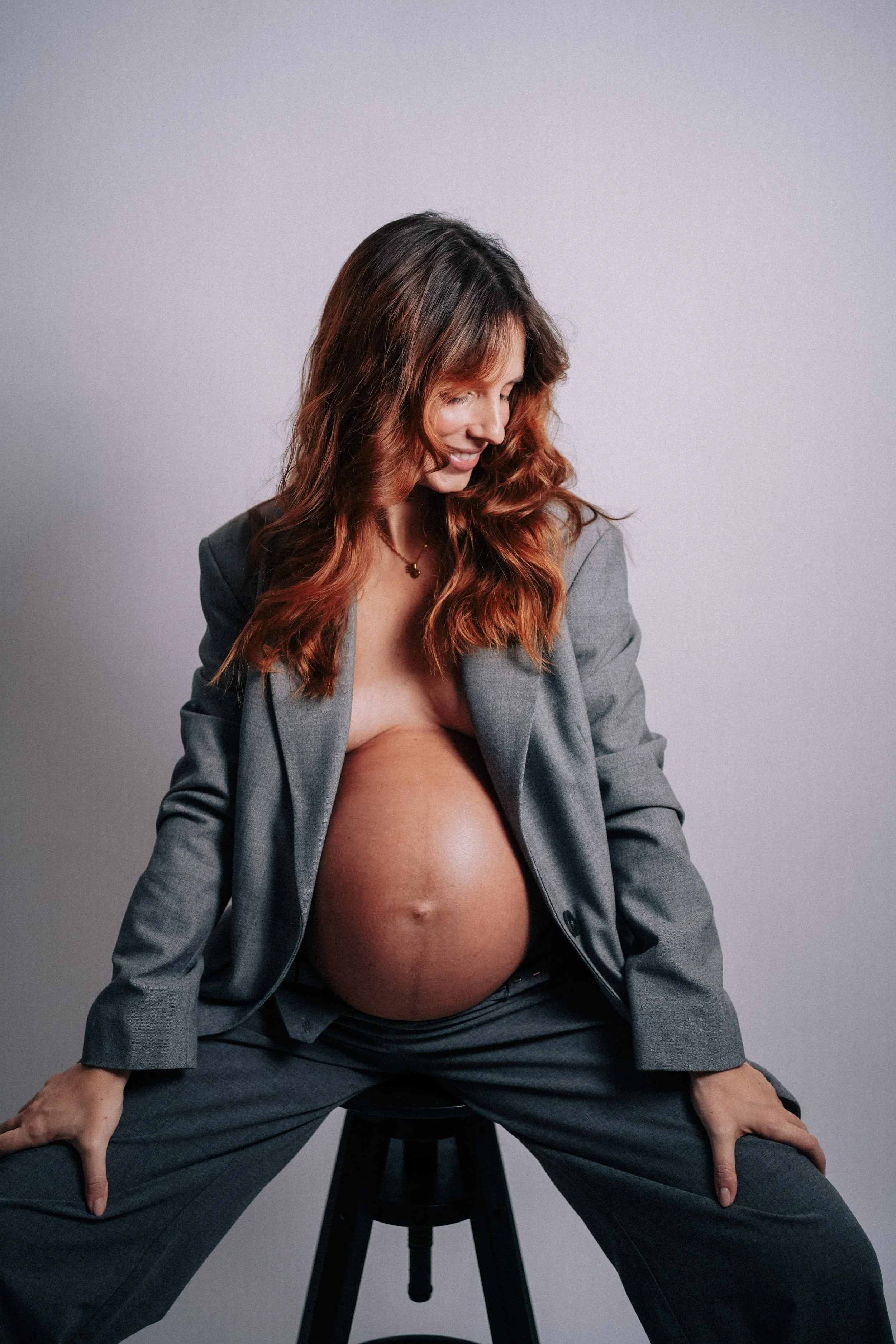 Close-up maternity photography detail of pregnant belly in white lace dress.