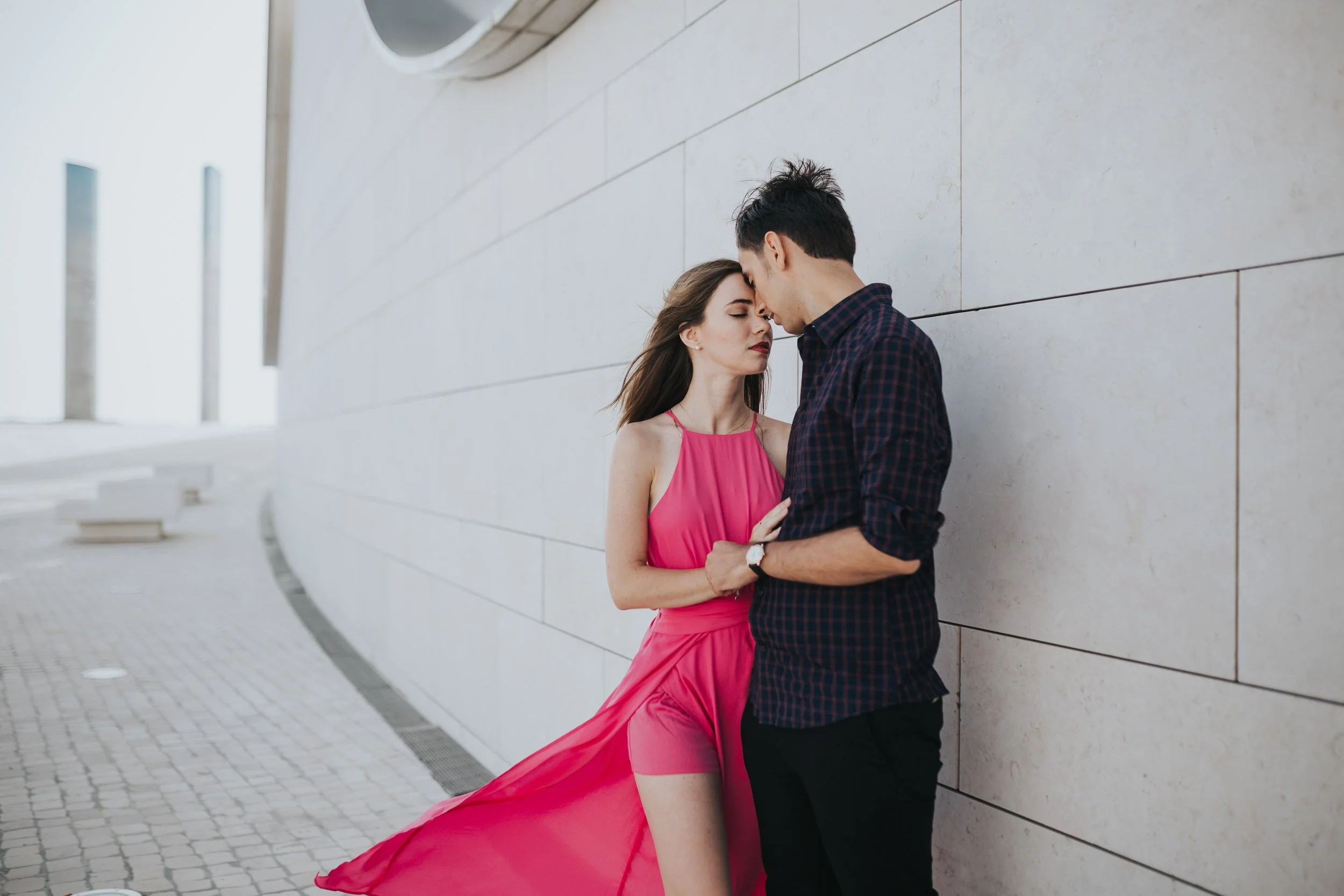 Engagement photography in Lisbon, couple embracing against modern architectural backdrop.