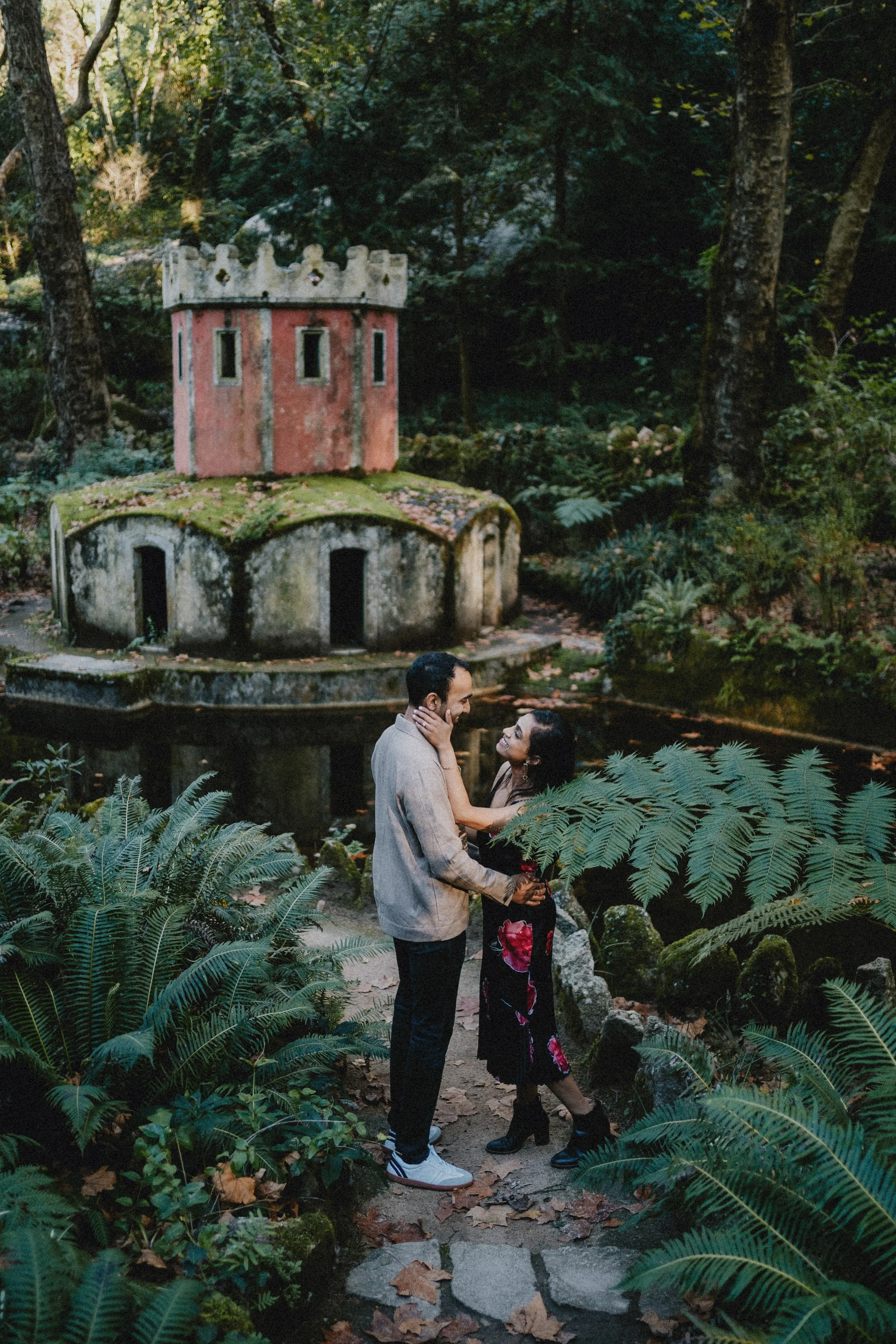 Engagement photography in Sintra, couple standing in lush gardens near historic palace.