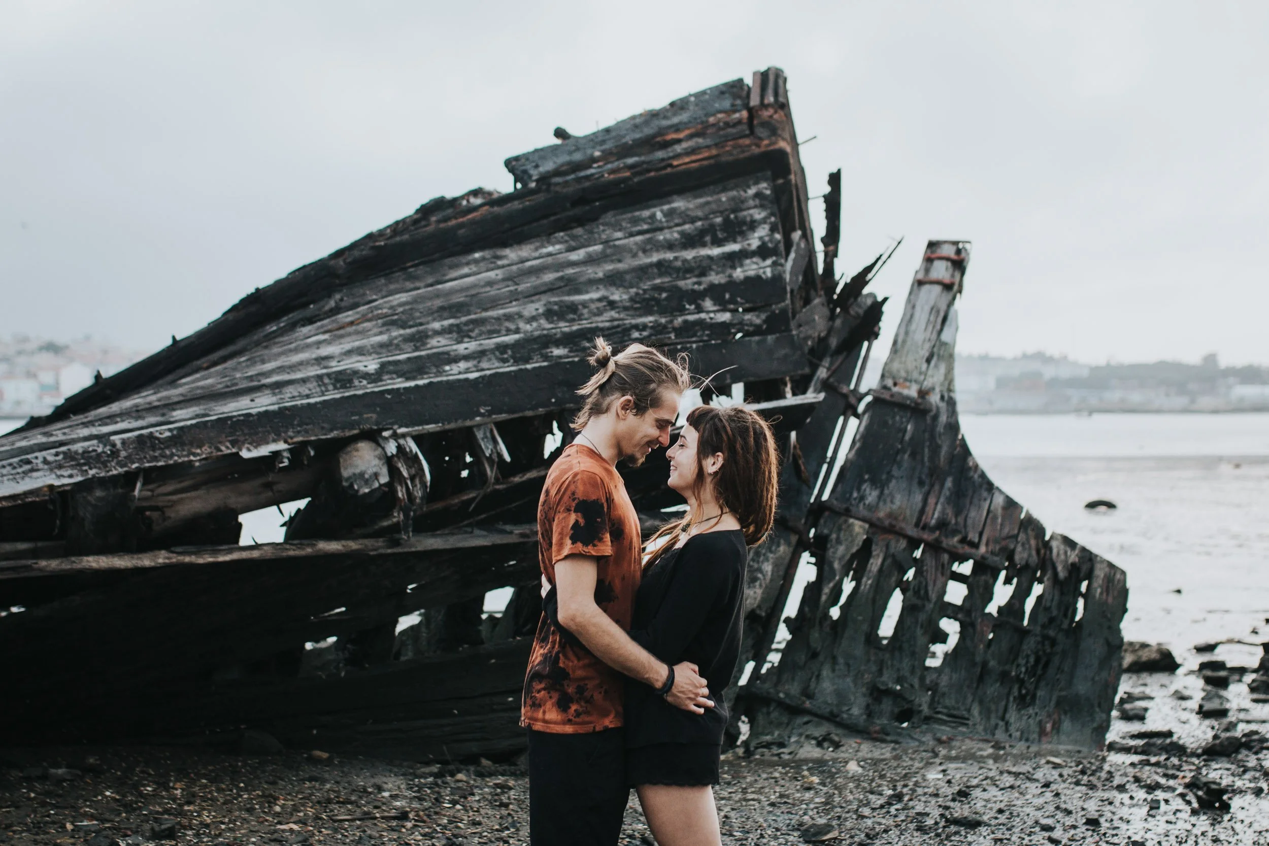 Engagement photography in Portugal, couple embracing near dramatic coastal landscape.
