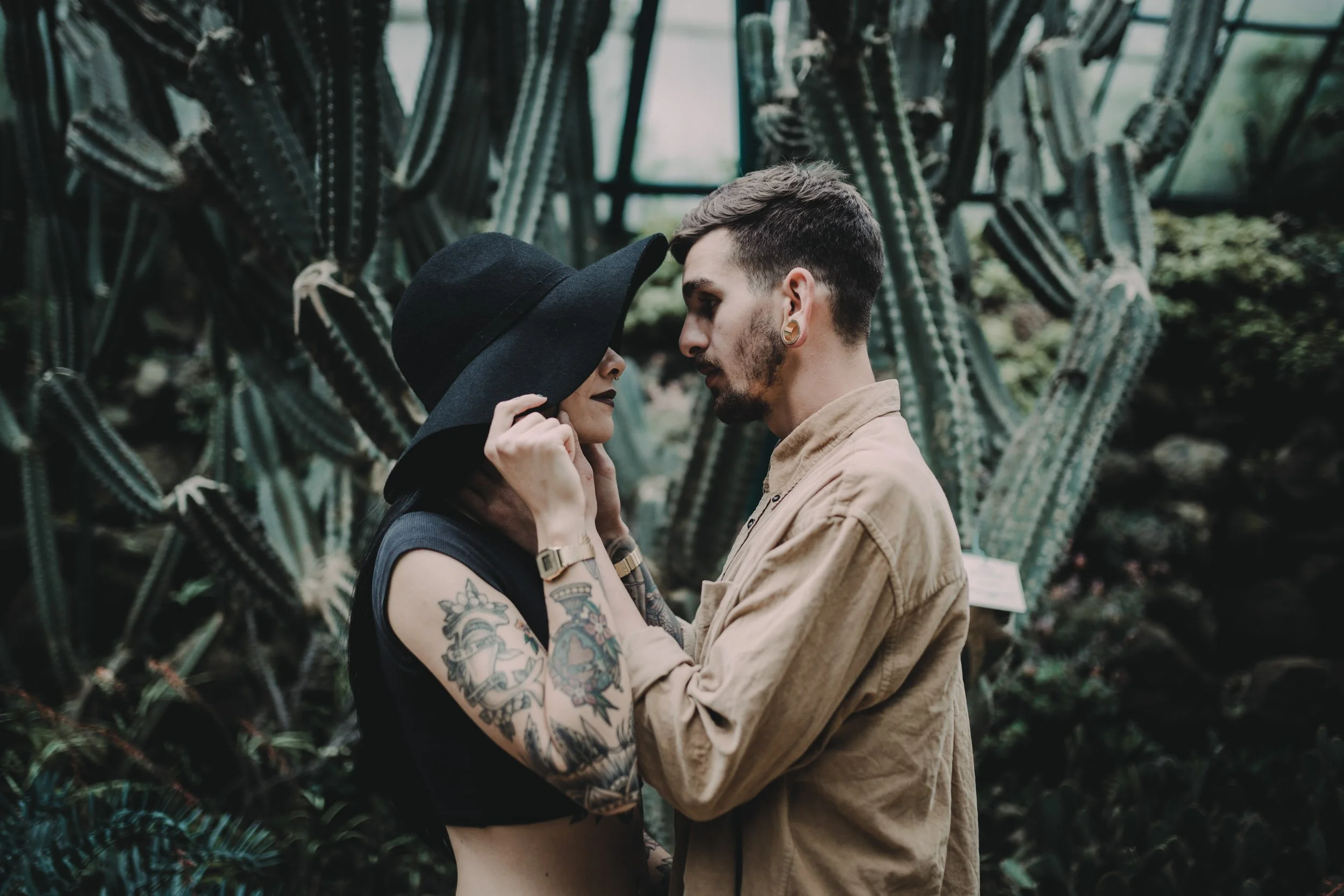 Engagement photography in Portugal, couple embracing in botanical garden surrounded by tall cacti.