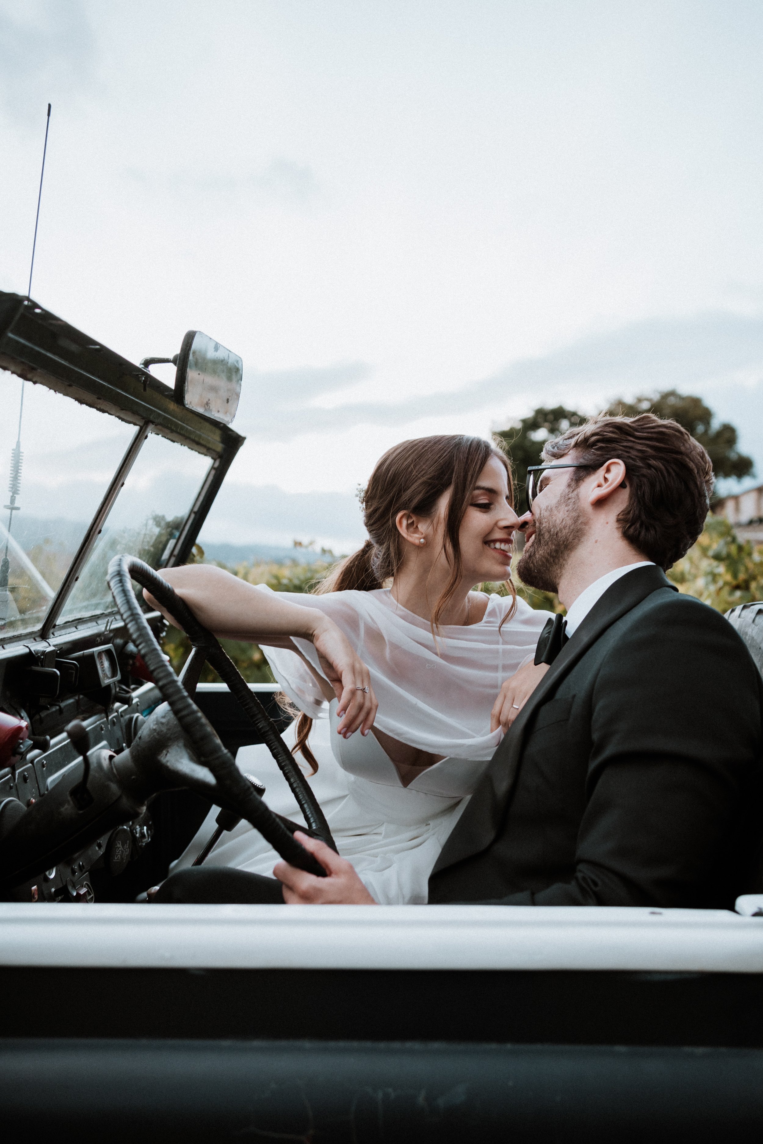 Romantic wedding couple kissing in vintage convertible car during destination wedding in Portugal