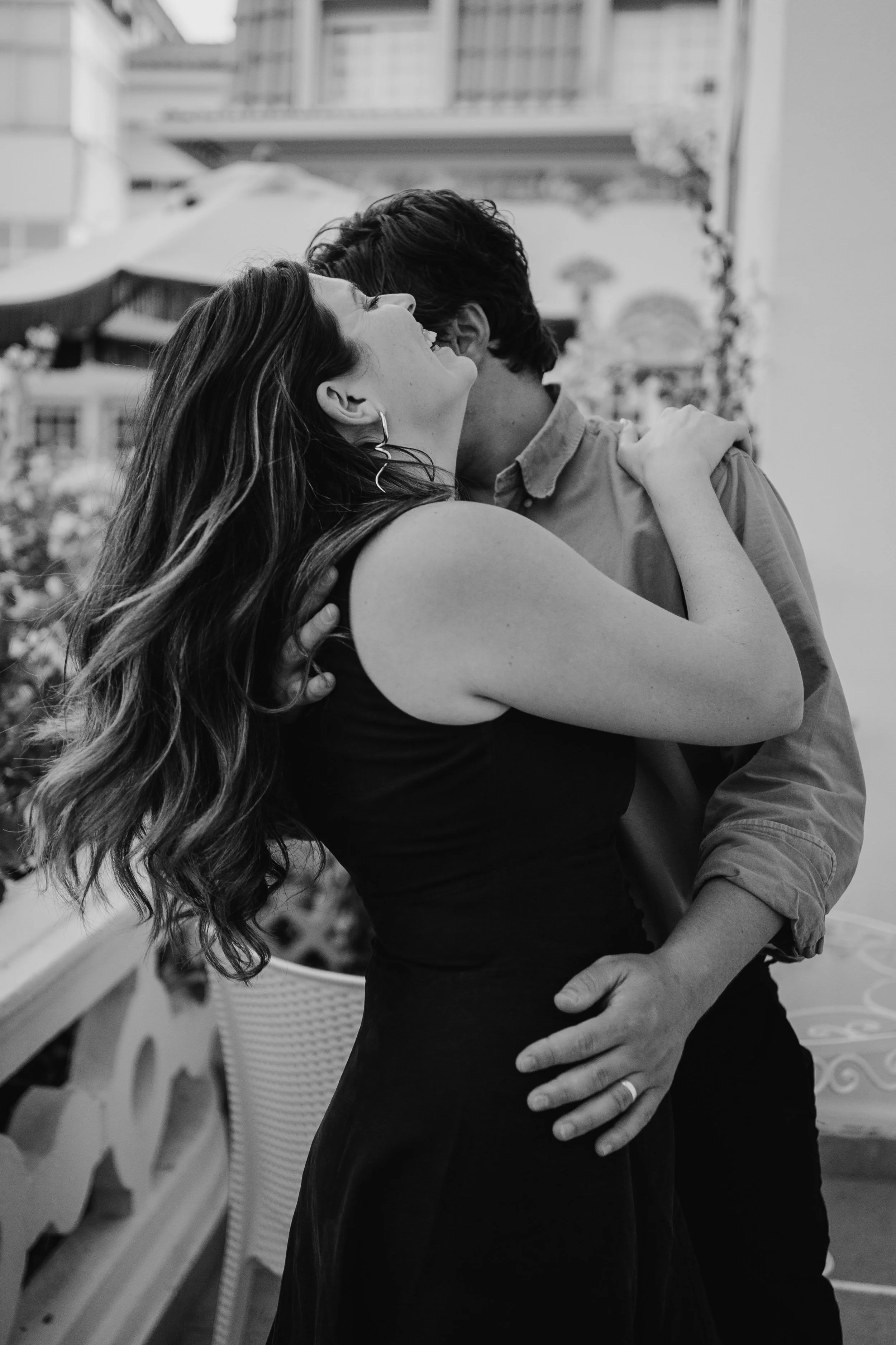 Black and white engagement photography portrait of couple sharing joyful embrace outdoors.