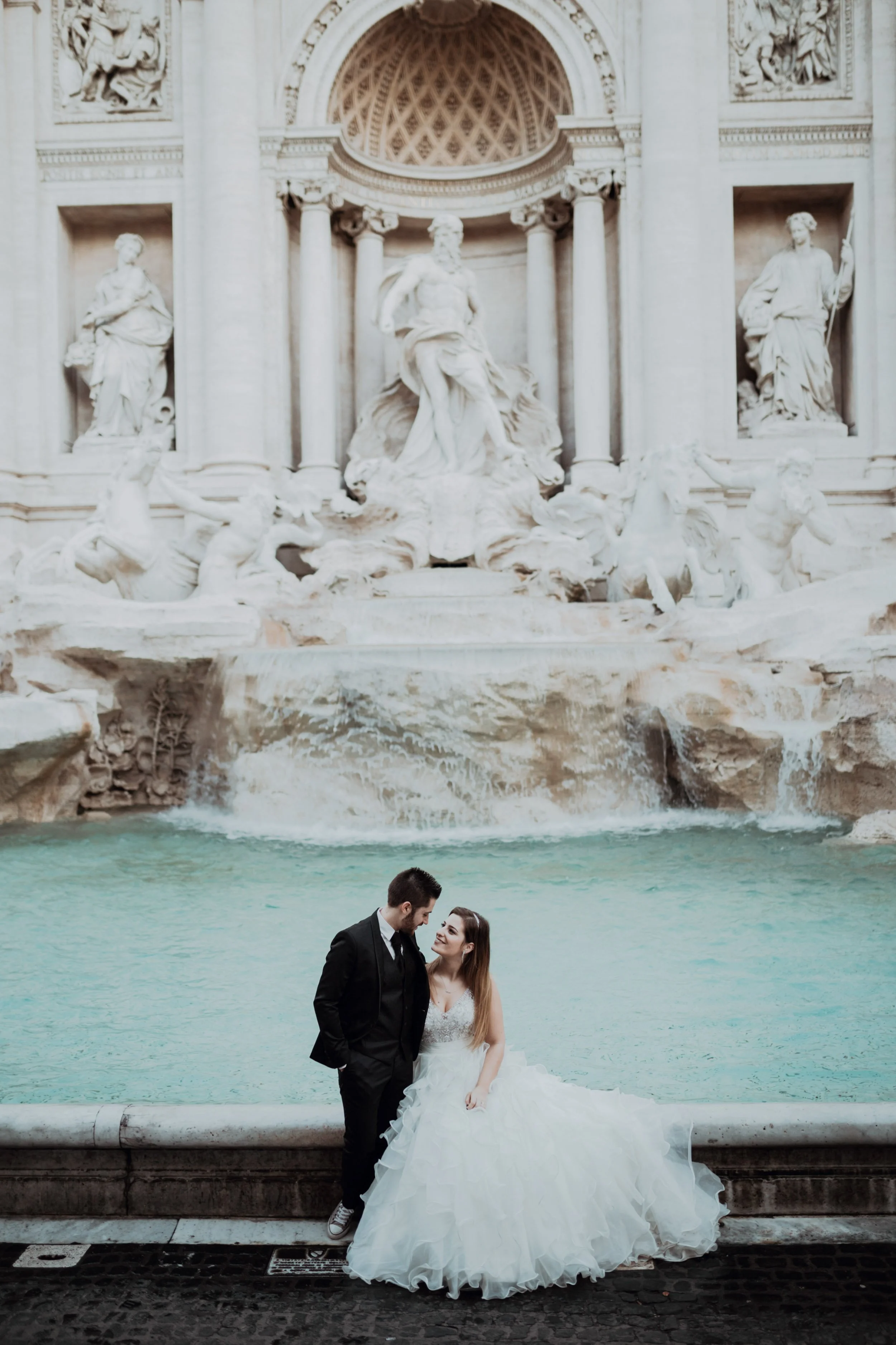 Bride and groom standing by the Trevi Fountain during Rome destination wedding