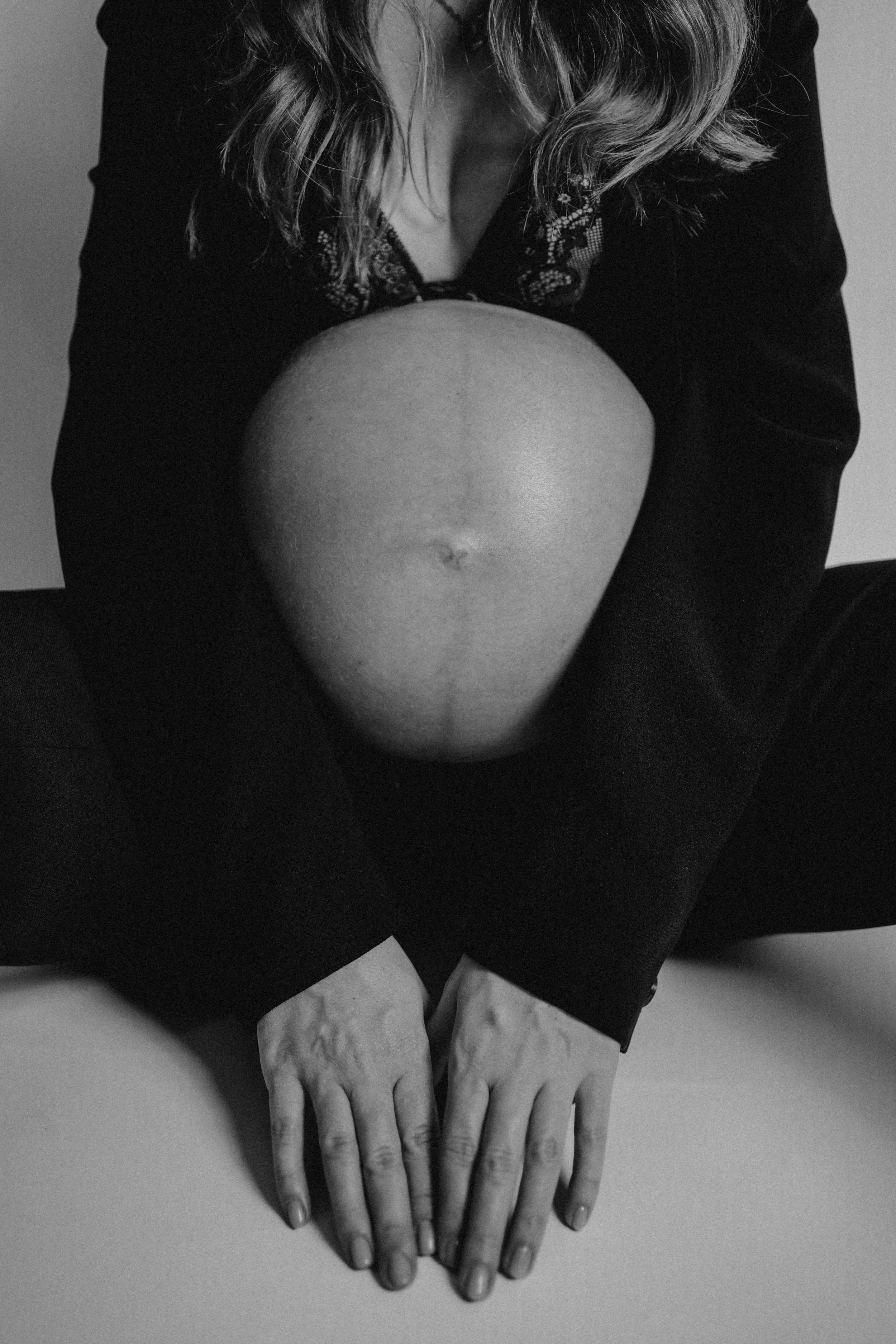 Minimal black and white maternity photography capturing artistic silhouette of pregnant belly.