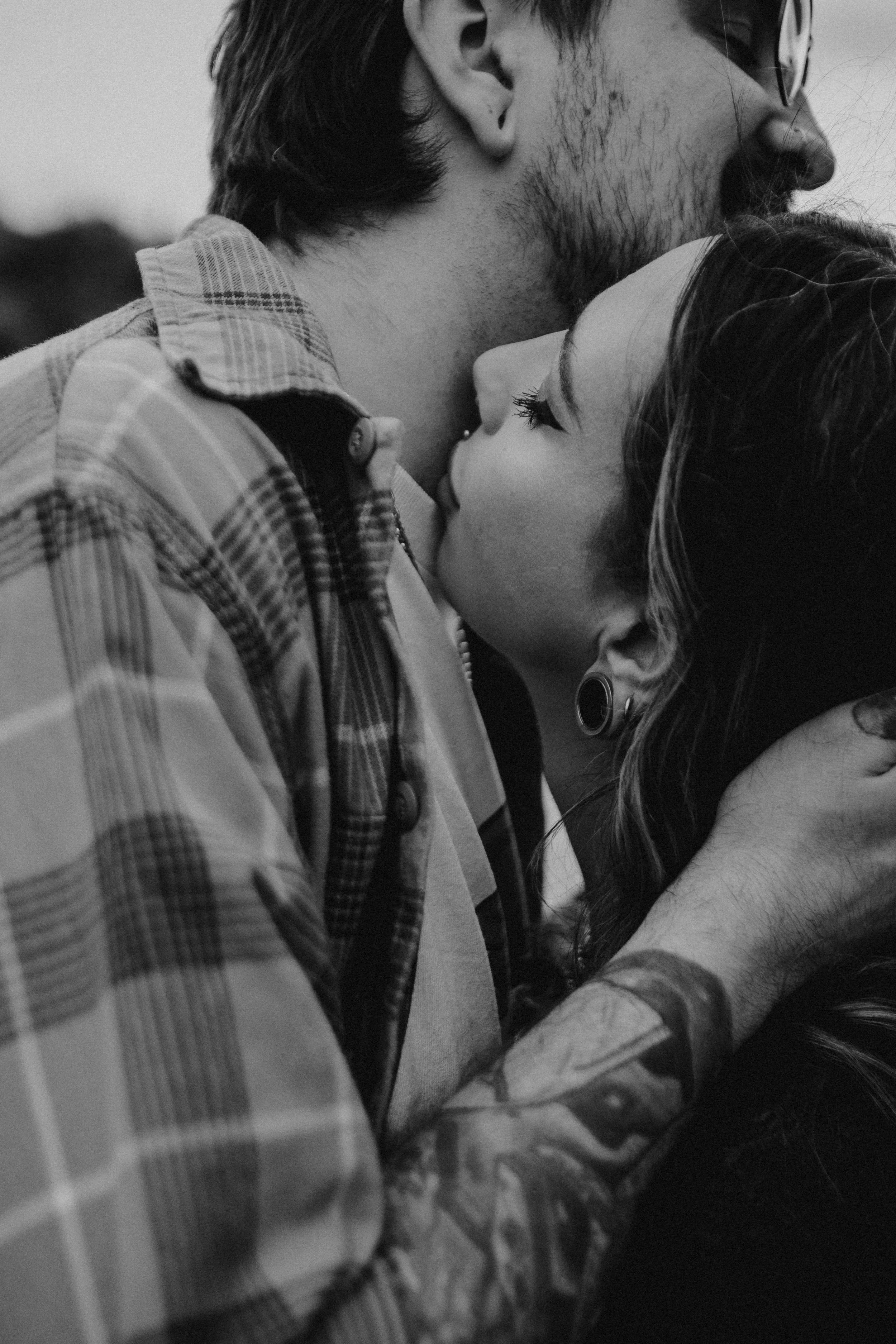 Black and white engagement photography portrait of couple sharing intimate kiss during candid session in London.