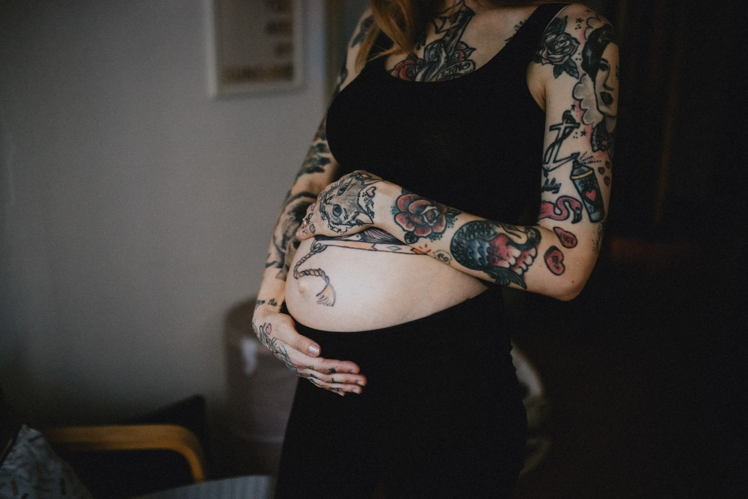Details of a pregnant belly, with tattoos