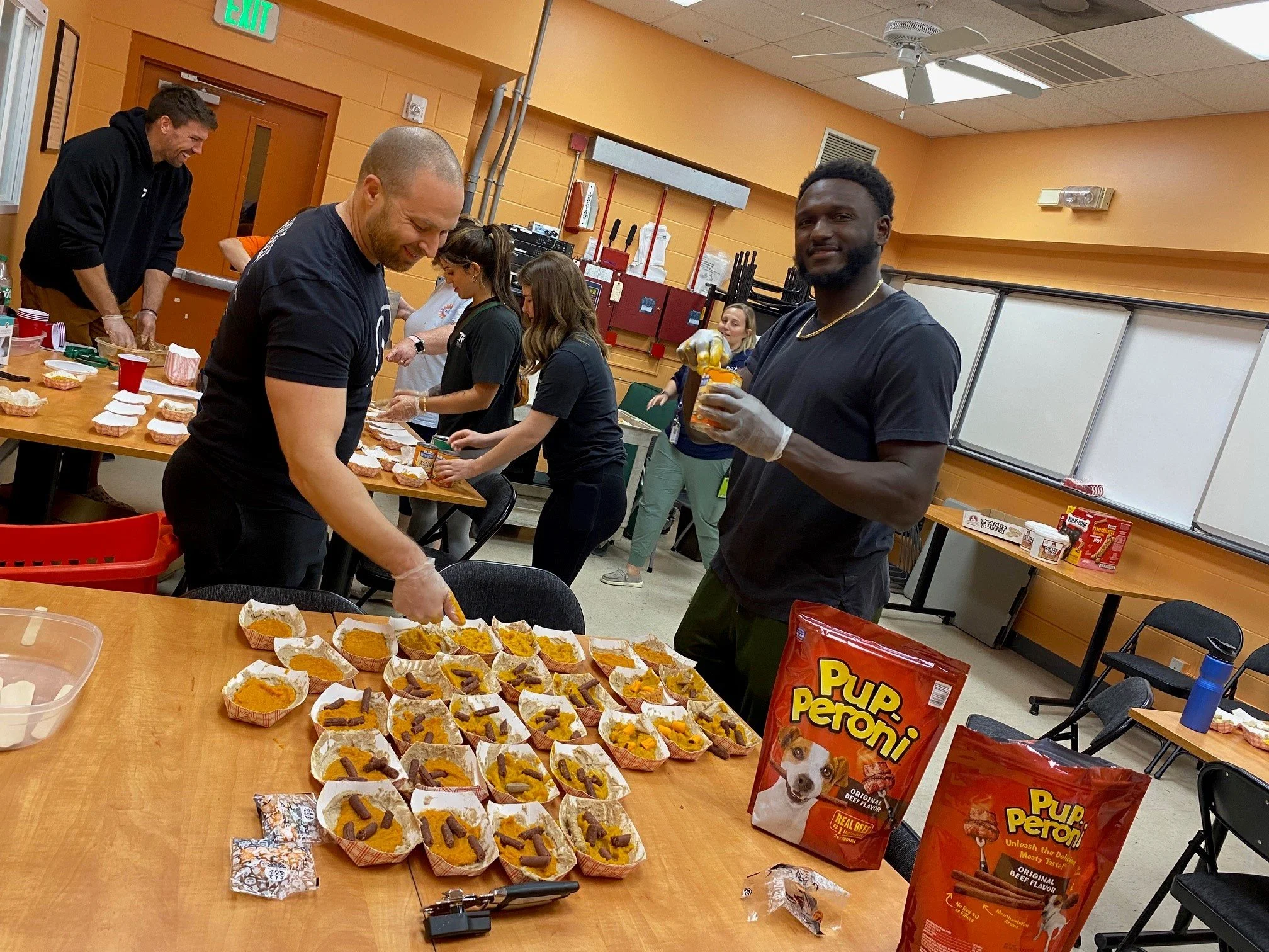 People preparing and packaging dog-friendly pumpkin treats in a classroom or meeting room.
