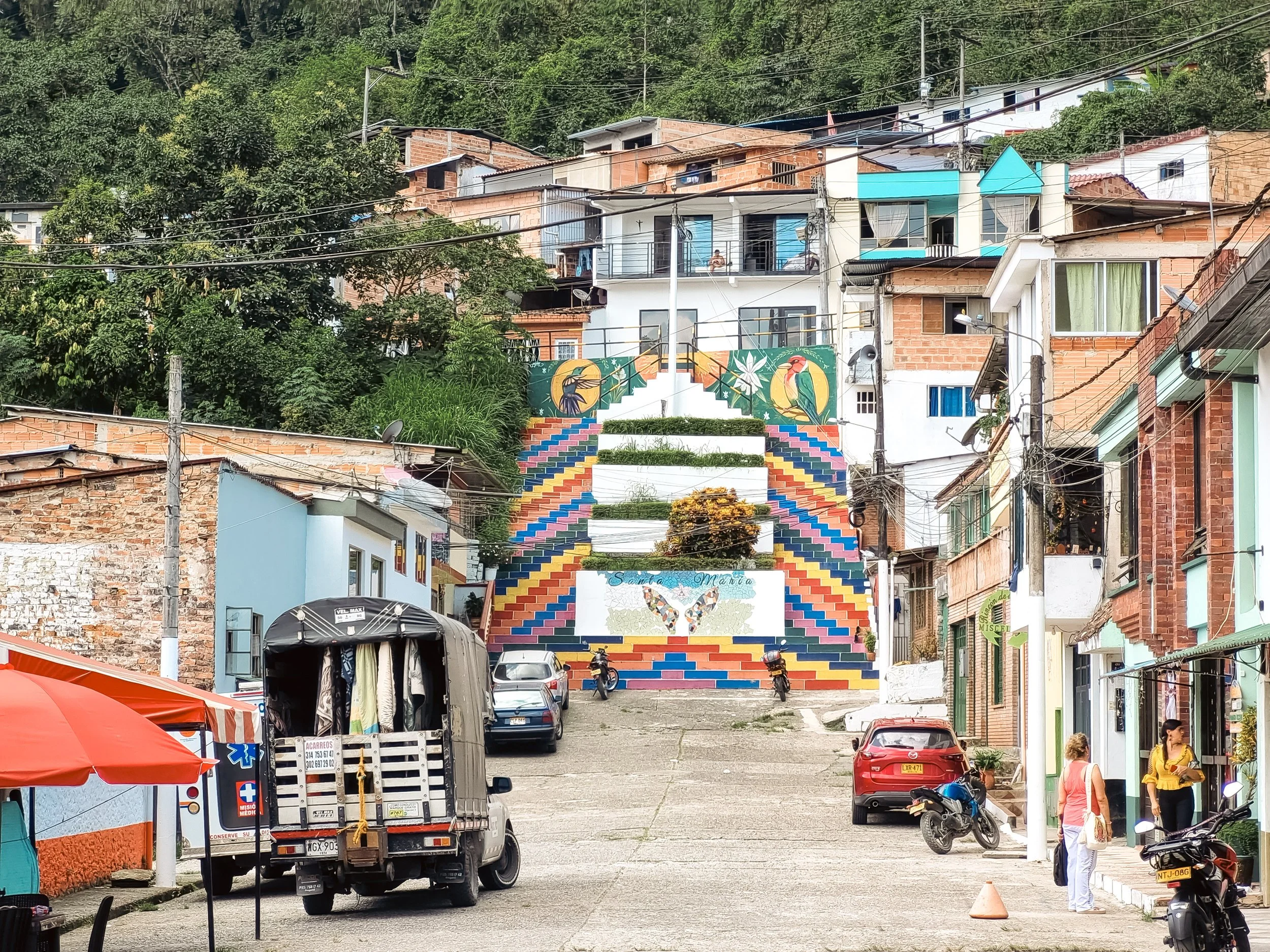 Colorful staircase leading up a hillside neighborhood with houses and people walking around.