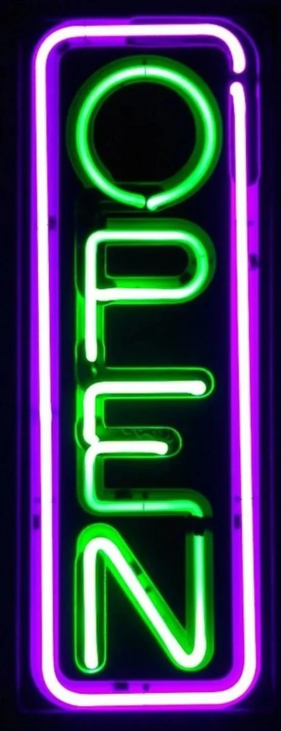 Neon sign that spells out "OPEN" with the letters vertically arranged in green and purple colors.