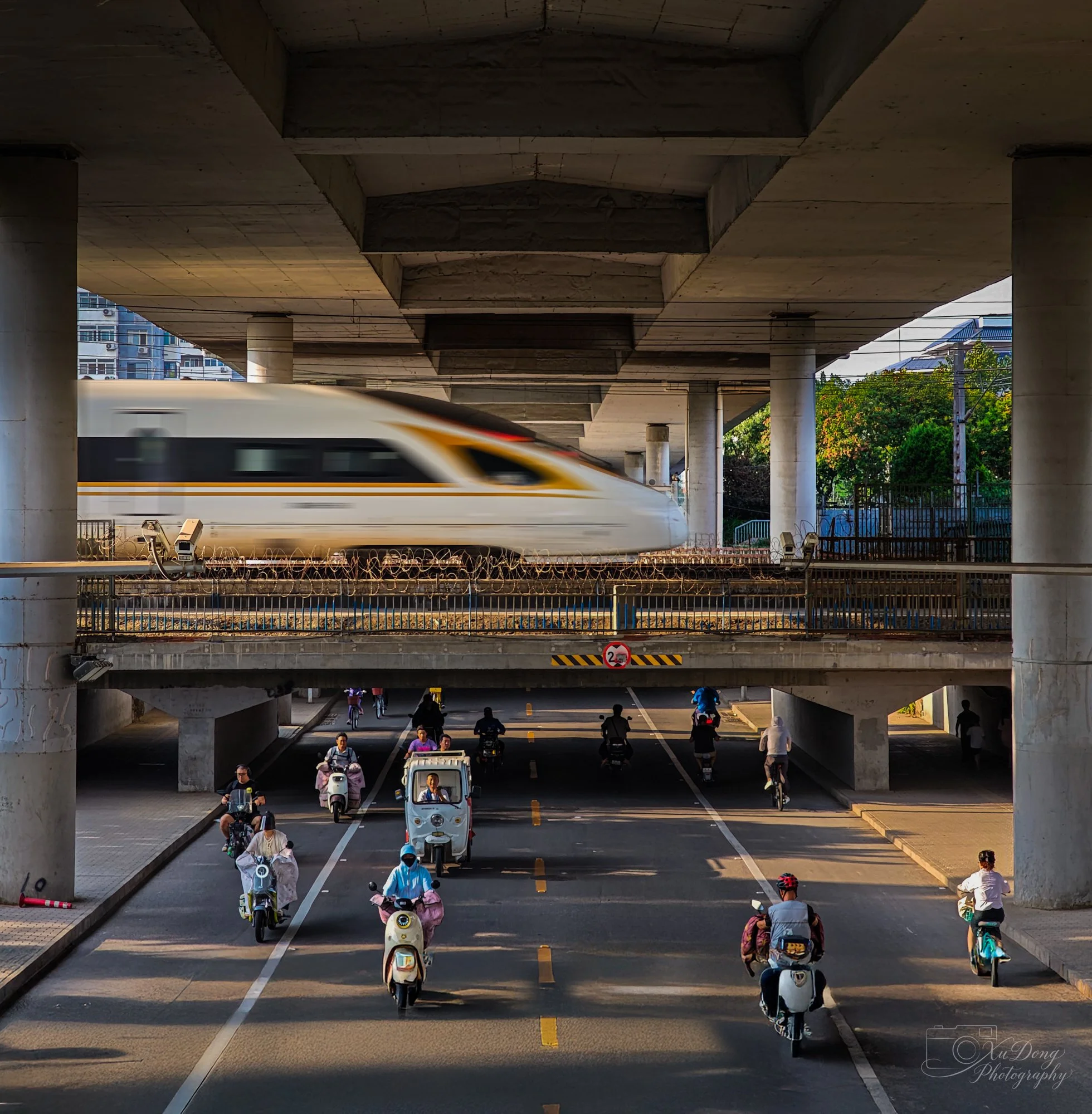 The layered pulse of modern China: a high-speed bullet train passing over the bustling, human-scale street life of Beijing
