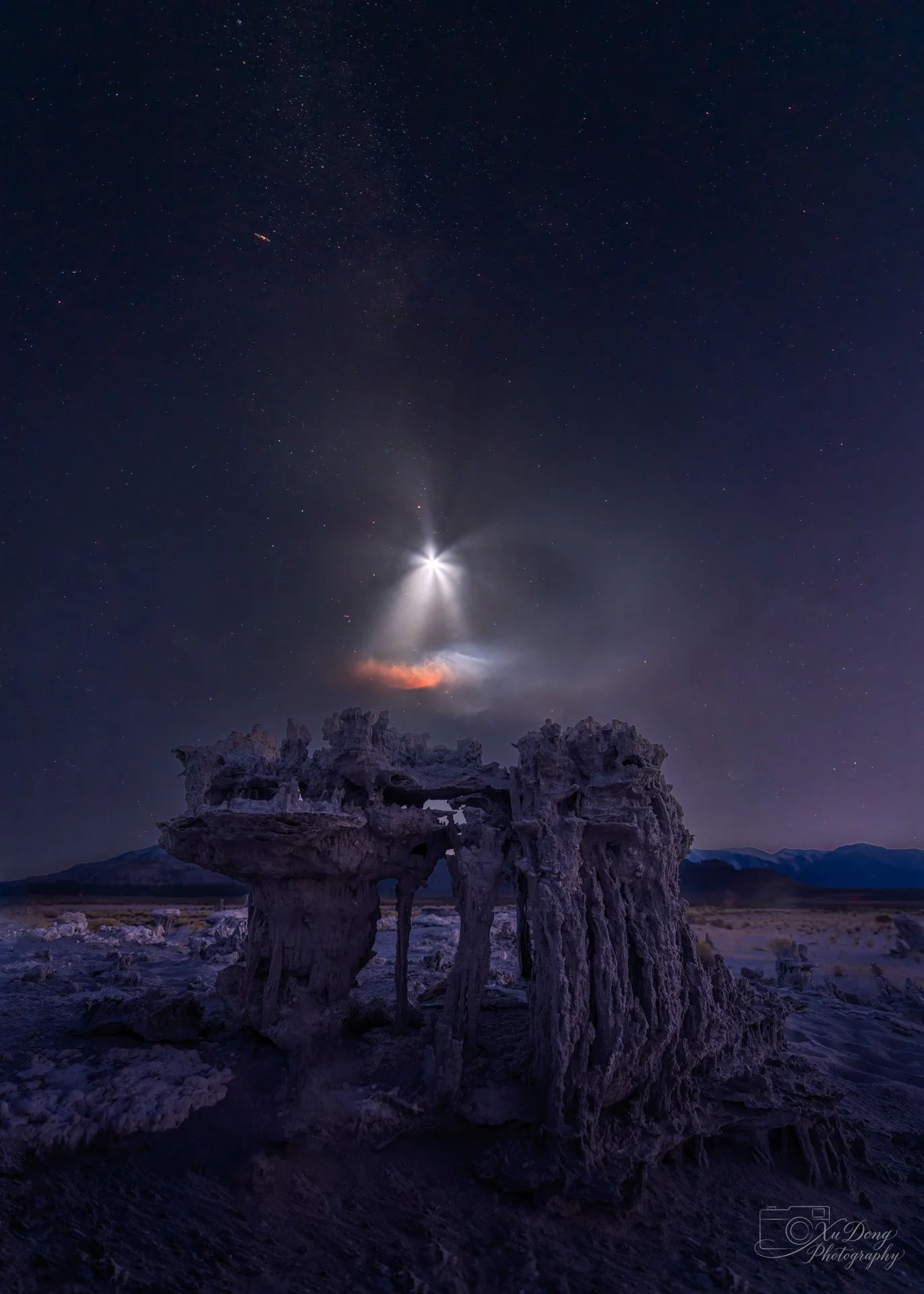 An extraordinary night photography shot at Mono Lake, California, capturing the prehistoric tufa towers alongside the unexpected "flower" plume of a SpaceX rocket launch.