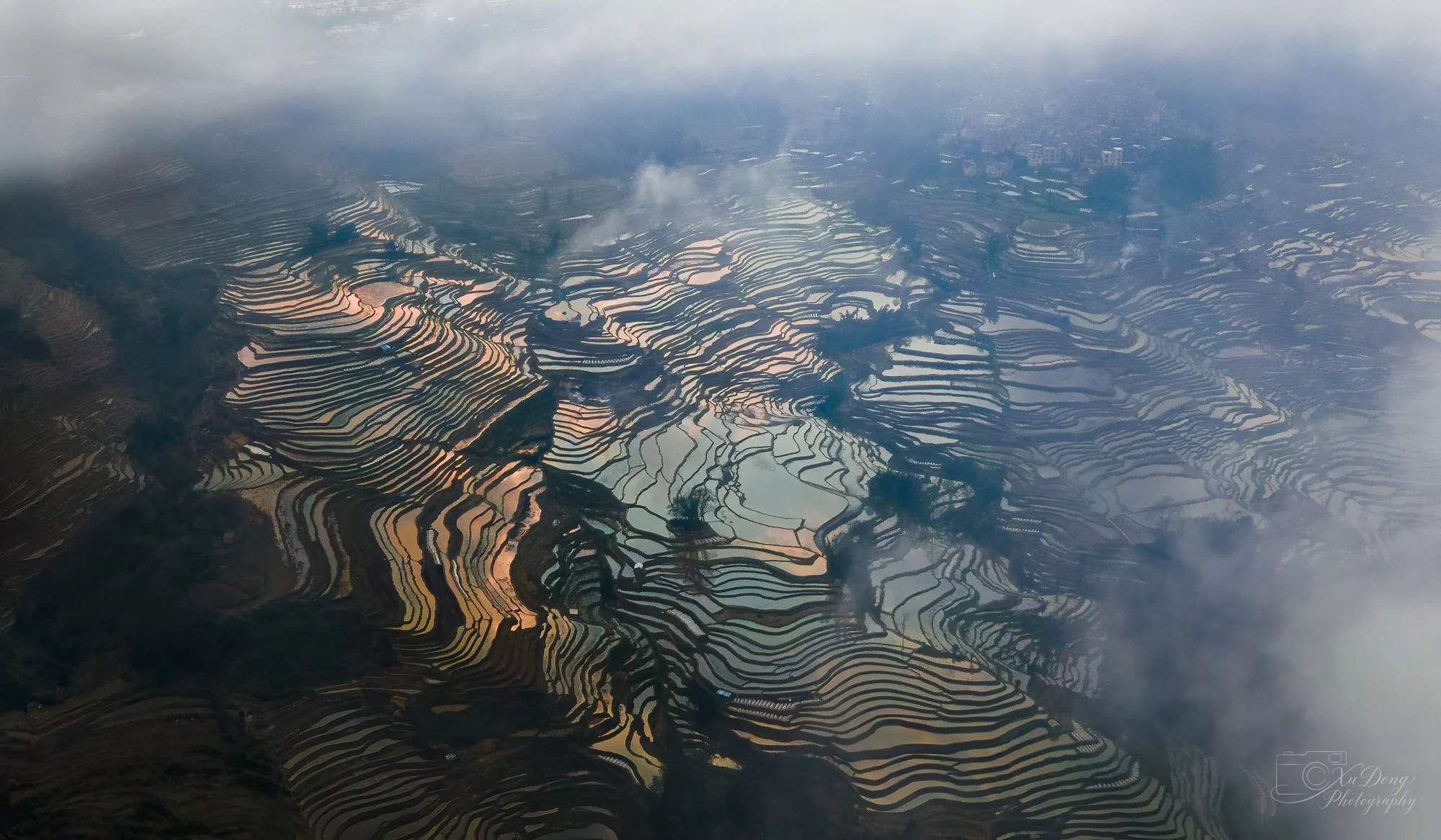 Fine art aerial photography of misty rice terraces in China, focusing on rhythmic patterns and fog