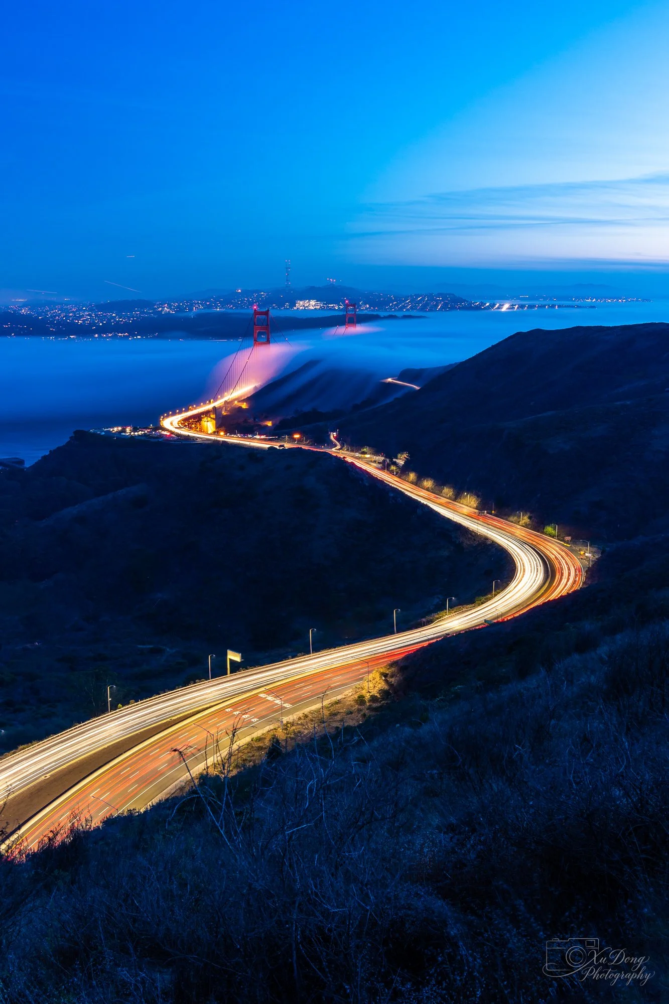 Winding road leading to the Golden Gate Bridge at dusk.